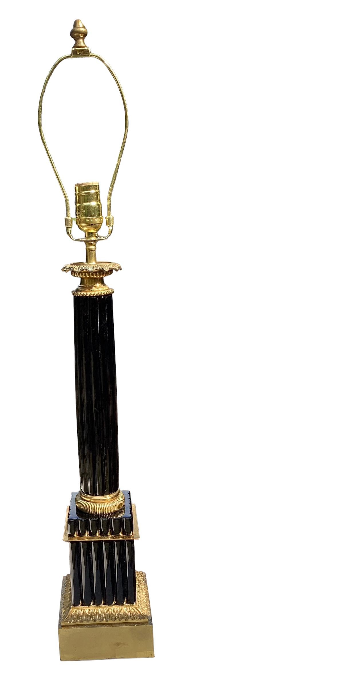 Lampada a colonna con canna in opalina nera francese di ottima qualità. La colonna a remi poggia su un basamento quadrato con montature in bronzo dorato. 
La lampada misura 23