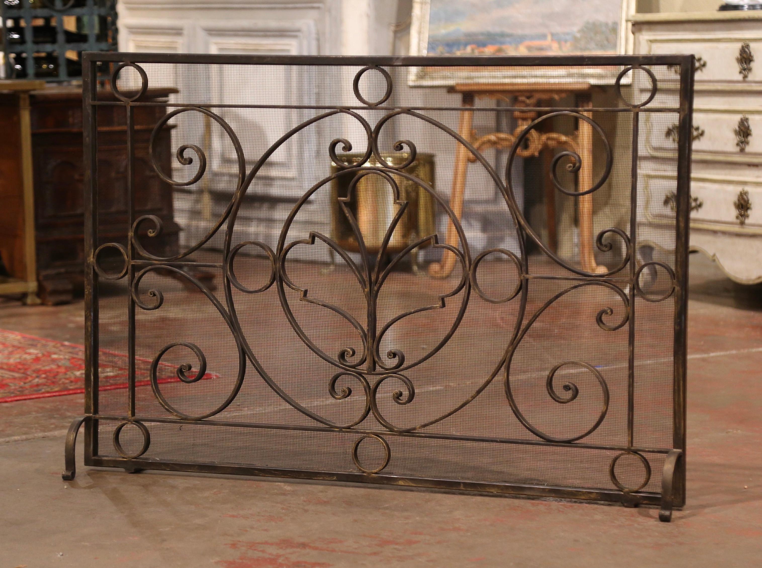 Decorate a fireplace hearth with this elegant freestanding vintage iron screen. Forged in France circa 1980, the important wrought iron screen stands on four scrolled feet and features decorative scroll work throughout; it is further embellished