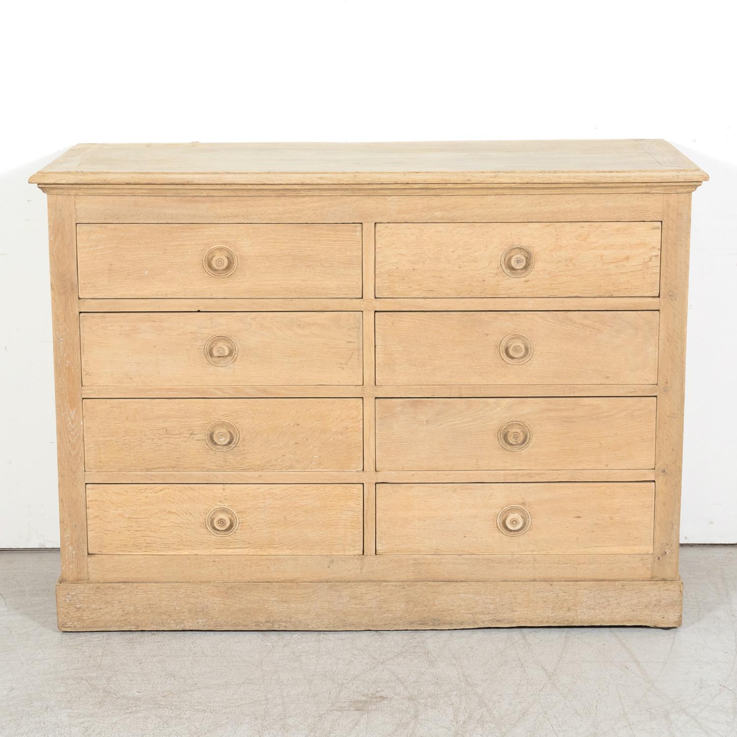 A vintage French meuble de metiers or workshop chest of drawers handcrafted of solid oak in Normandy, circa 1940s. Having a bleached finish, this handsome chest features a bank of eight drawers with their original round wood knobs. The chest has a
