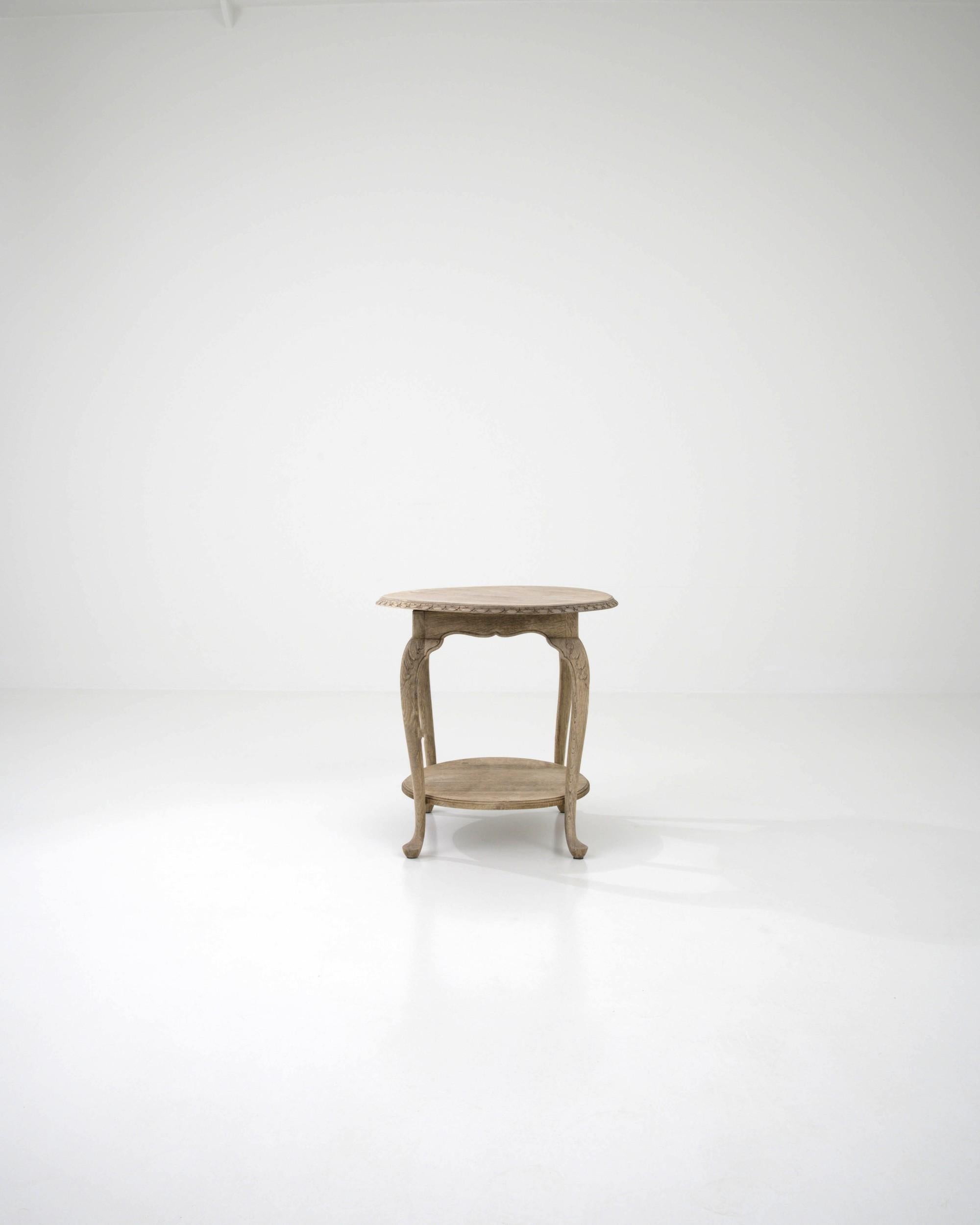 Made in France in the 20th Century, this oak side table is defined by the shape of its round table top. The subtle organic feel of the ovoid top is enhanced by the table's finish and its decorative elements. Natural oak has been enhanced with a