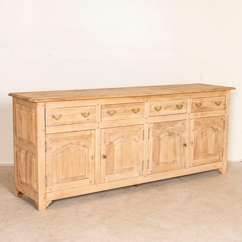 This vintage long oak sideboard has been bleached giving it a fresh and welcoming look for today's modern home. The four drawers have large pulls and rest over four arched panel doors. While crafted in the late 20th century, the traditional French