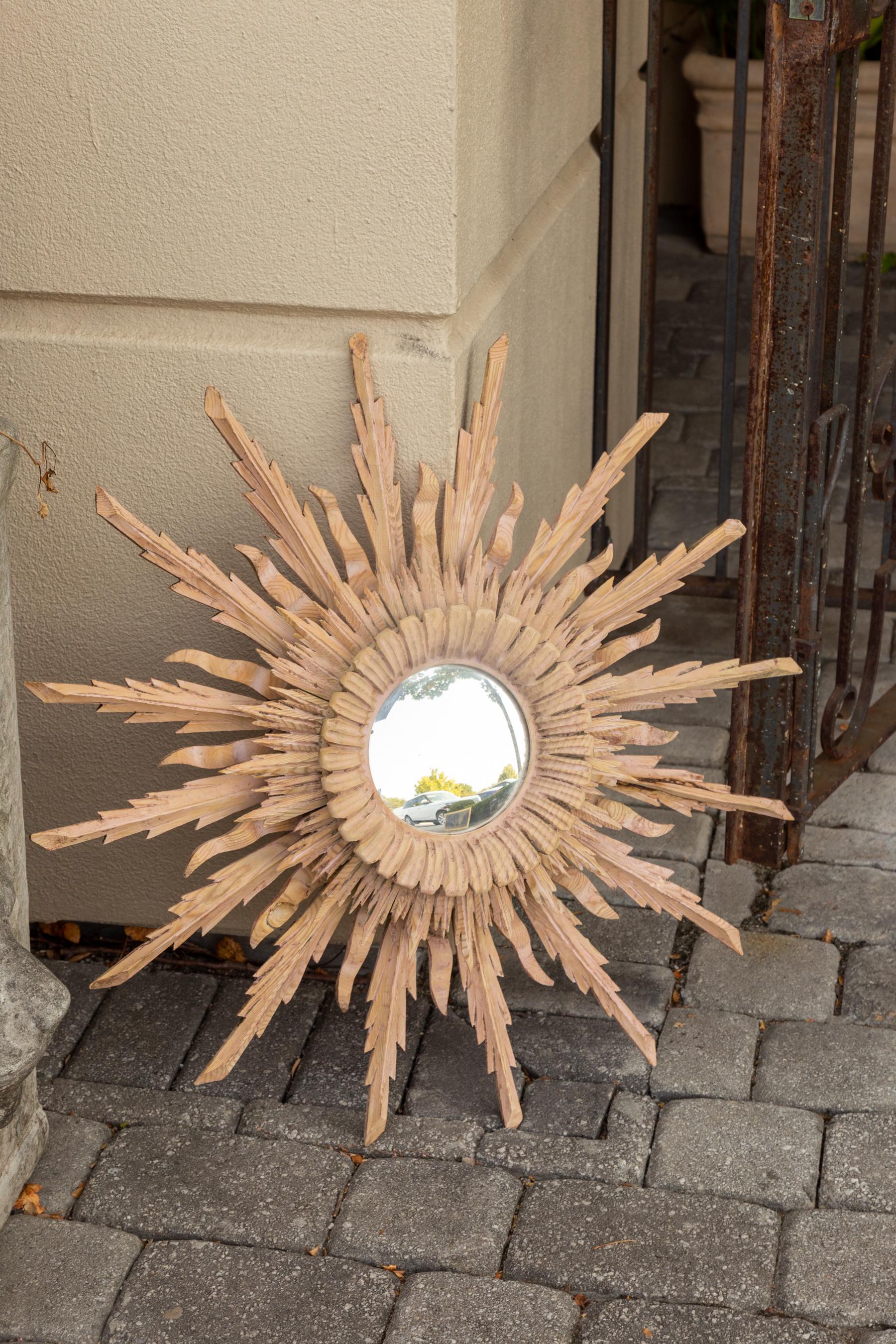 A French vintage bleached wood sunburst convex mirror from the mid-20th century, with rays of varying heights. Born in France during the mid-century period, this exquisite mirror charms us with its unusual bleached finish and graceful lines.