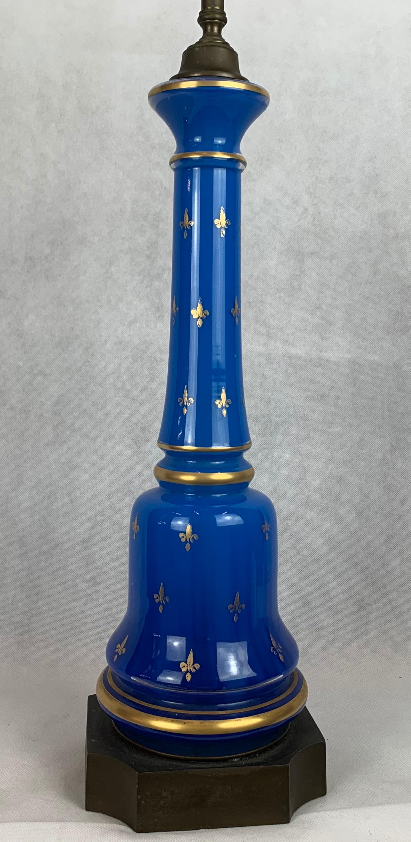  French blue opaline glass lamp mounted on a black base. The lamp has gold fleur-de-lys painted on the exterior.
Shade not included.
Measurements: Glass portion of lamp 18.25