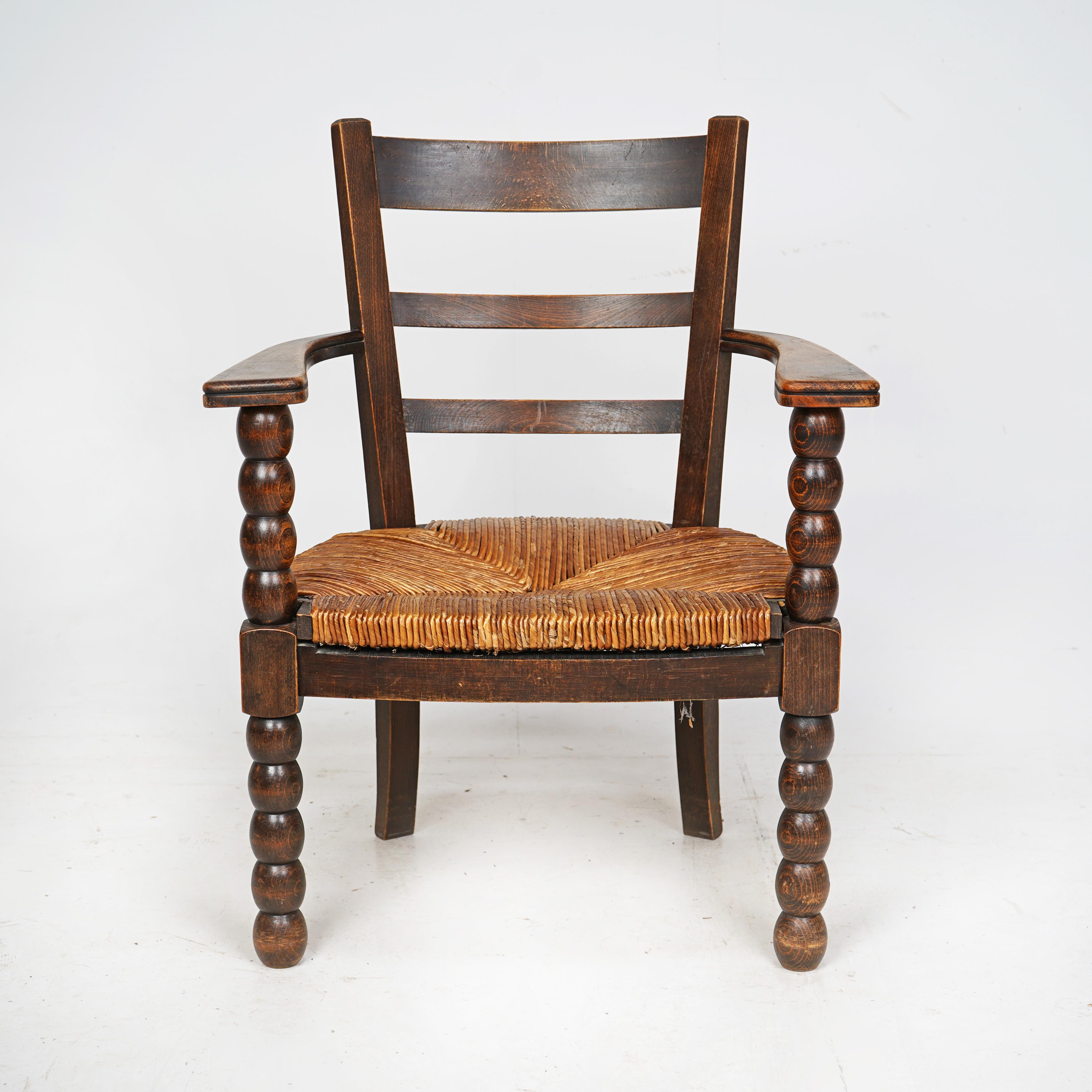 Well proportioned French bobbin turned armchair with rush seat. 
Made from oak this armchair has worn well and has a nice patina. The rush seat is in good condition and the chair is solid. 
French Circa 1950s. 

Height - 80cm
Width - 61cm
Depth -