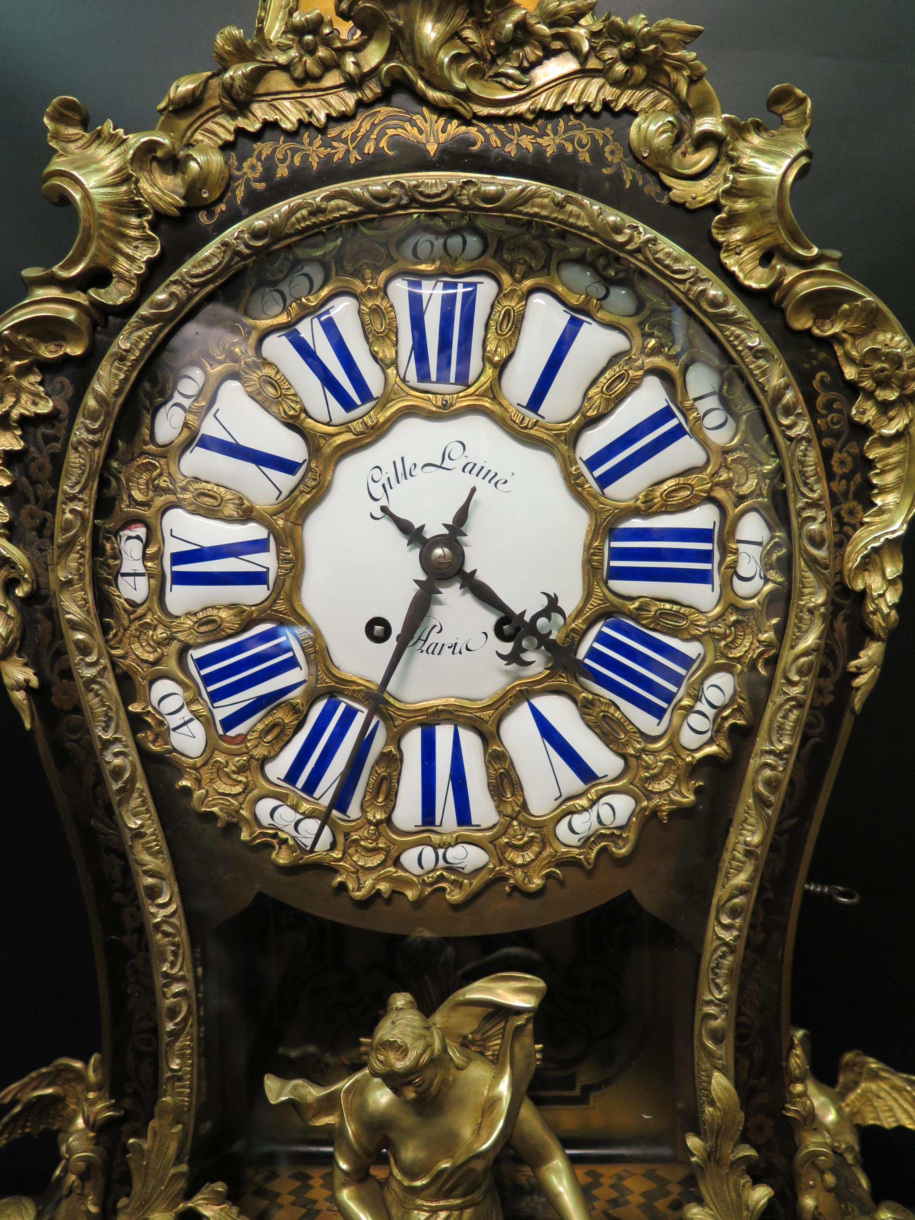 This vintage early 1900s French oversize Boulle clock is beautifully designed with a decorative bronze & inlaid case. This inlaid Boulle work is a floral motif that subtlety highlights the elaborate sculpted ormolu decorations. These decorations