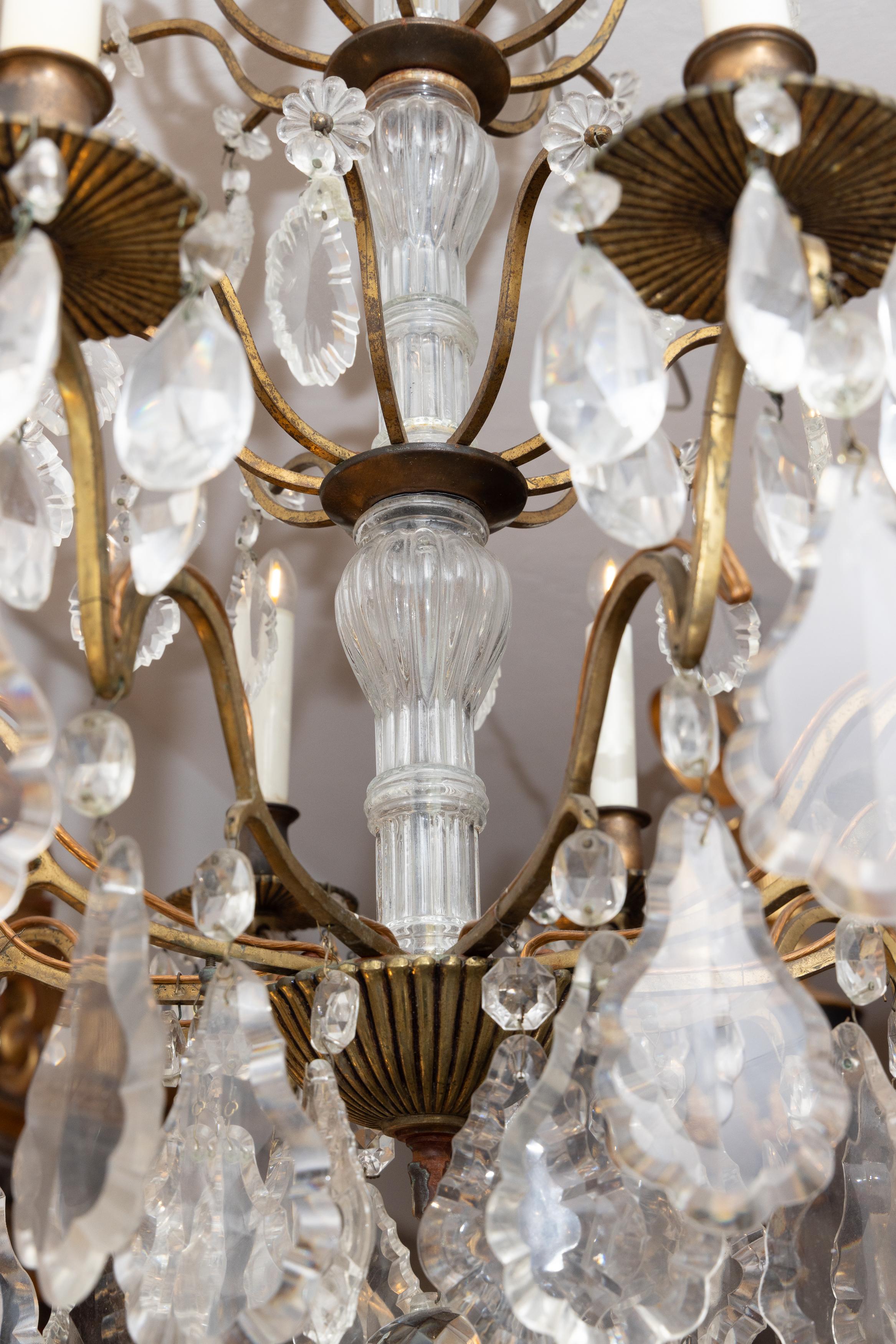 Si tratta di un grazioso lampadario francese a 10 luci in ottone con bracci contenenti una serie di pendenti in vetro che emanano da uno stelo centrale in vetro.
