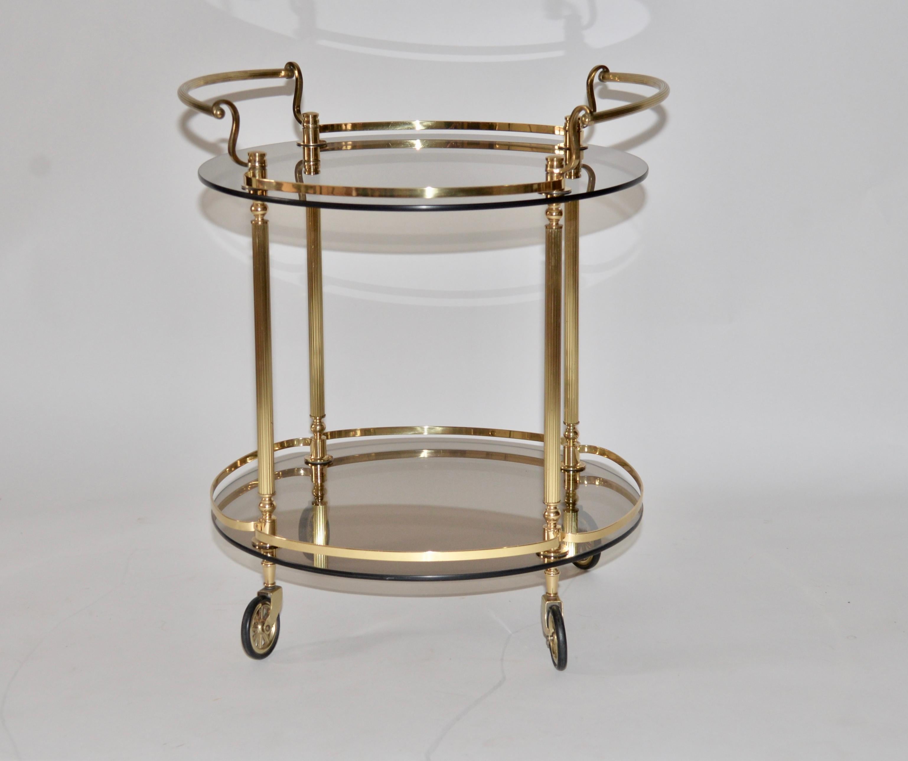 A French vintage polished brass and smoked glass drinks/serving trolley. This item has polished brass fluted uprights and two shelves. This is a lovely classic timeless item.
