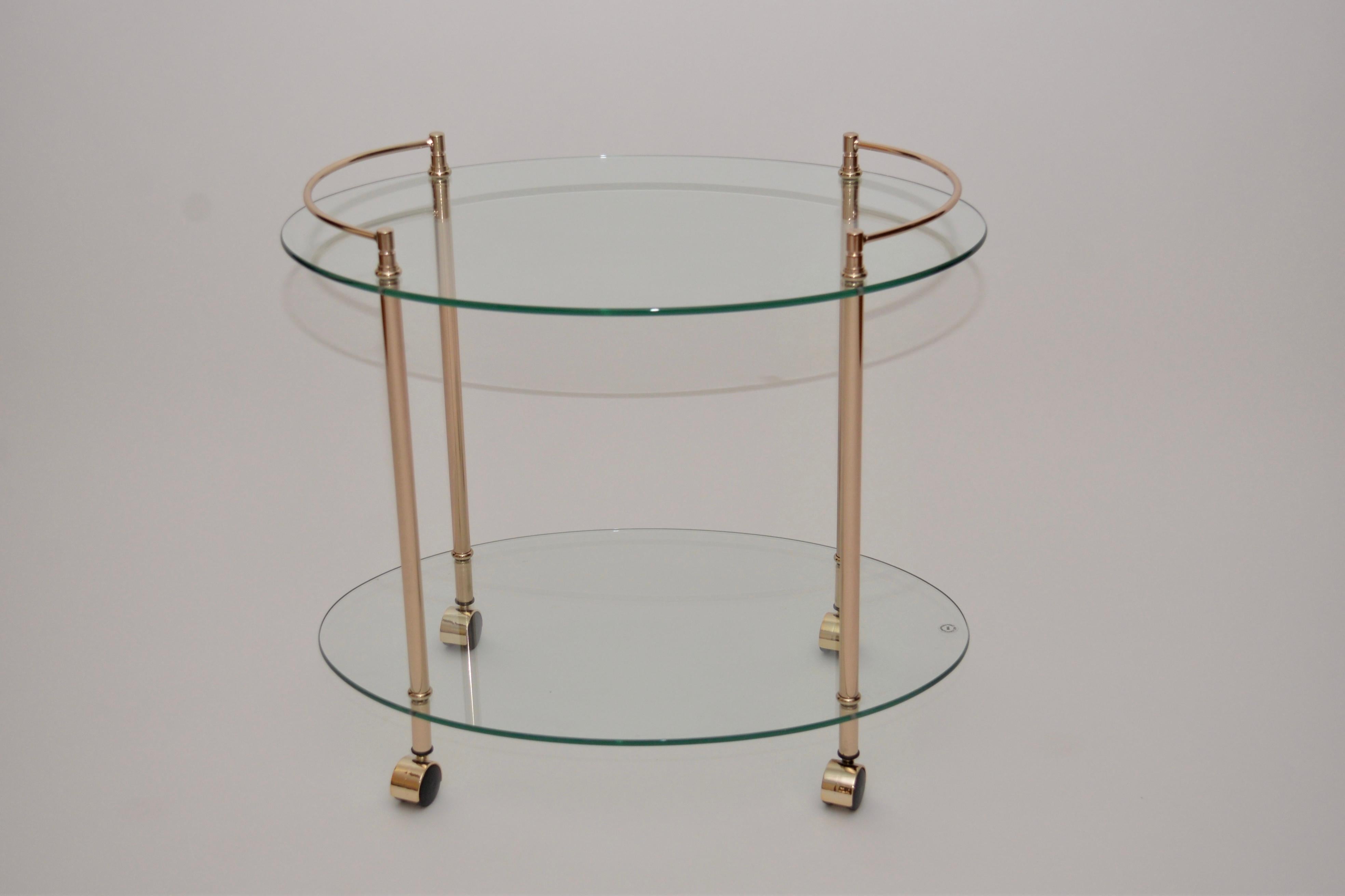 A vintage French polished brass and glass drinks/serving trolley, circa 1980s. This trolley is a Classic oval shape with two-tier tempered glass shelves.