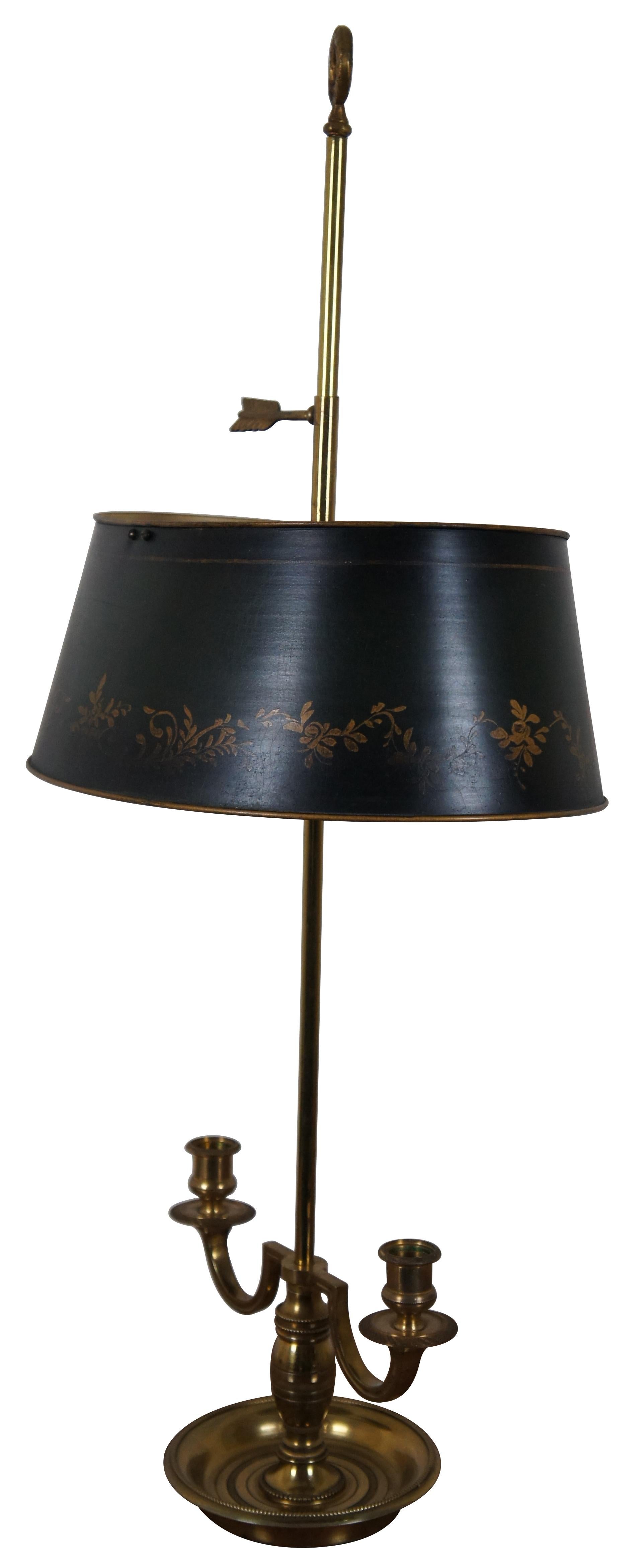 Vintage mid-20th century French bouillotte style two light table lamp featuring a brass double candlestick base, arrow and wreath finial, and hand painted black and gold tole metal shade. Measure: 29