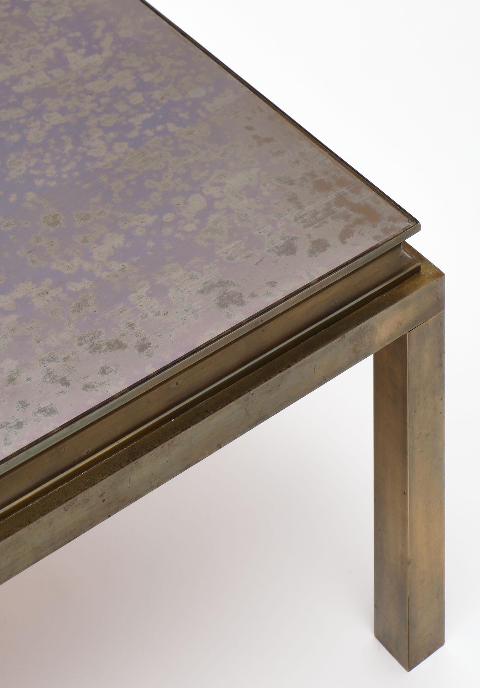 French vintage brass coffee table with a patinated solid brass base and the original eglomised gold glass top. We love this solid, impressive piece!