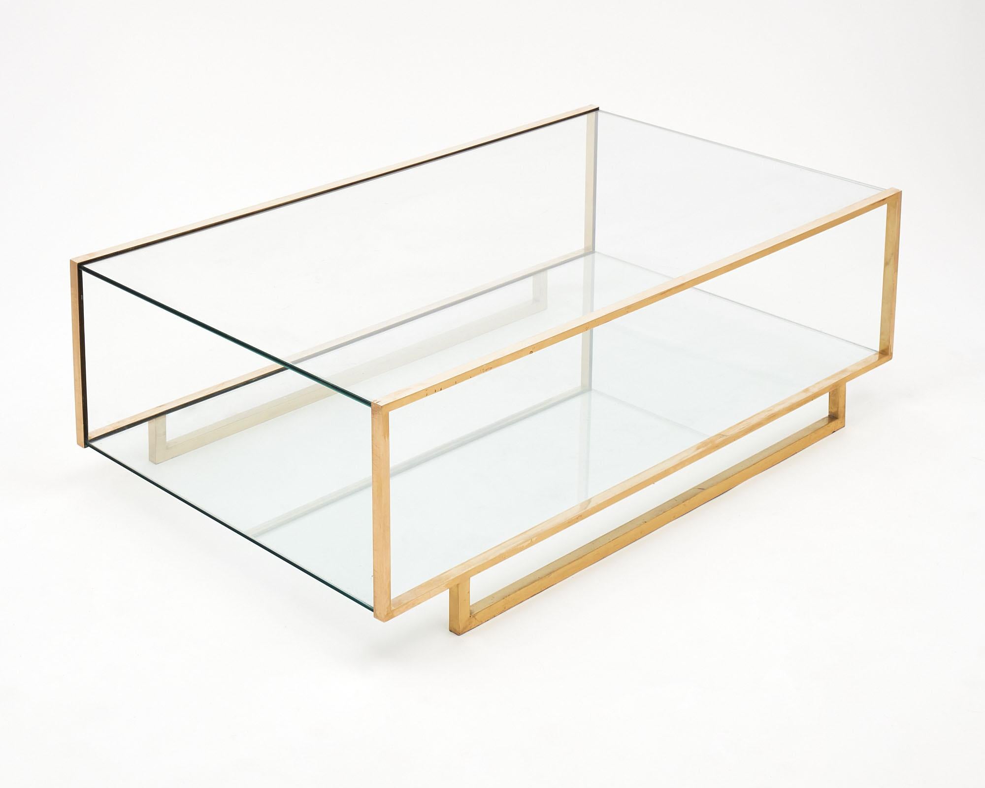 French coffee table made of brass and glass. There are two shelves of glass with glass on each end; creating a vitrine like case. We love the striking lines of this piece!
