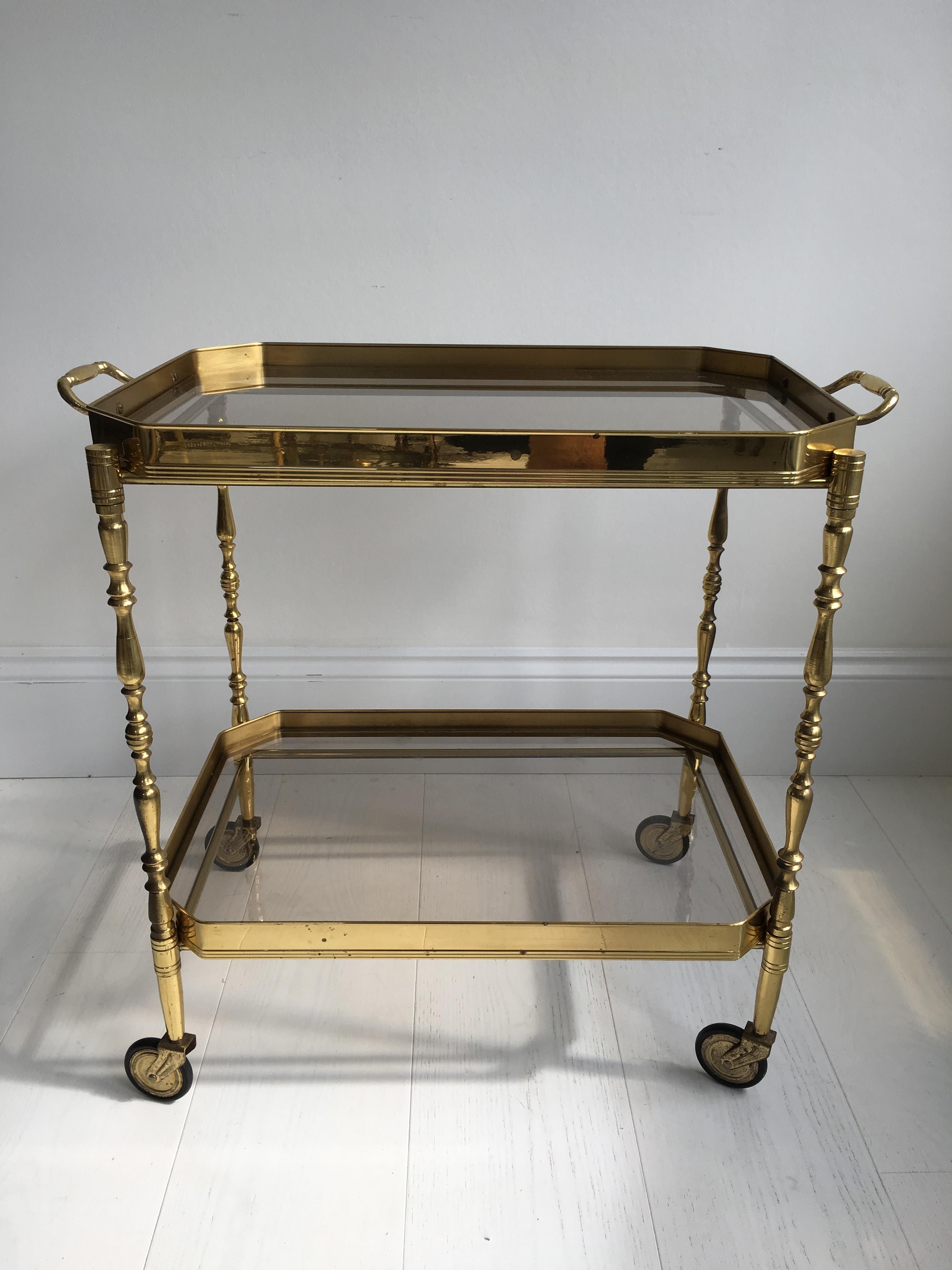 Vintage drinks trolley from France, circa 1950.

Lacquered brass frame with lift off top tray 

Perfect for smaller spaces

Measures: Overall dimensions 62cm wide (incl handles), 36cm deep and 56cm tall (54cm to glass).