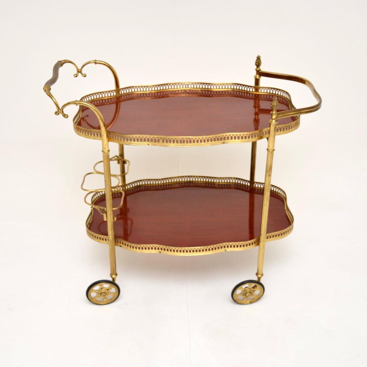 A stylish and very well made vintage French drinks trolley, dating from the 1950’s.

It is beautifully constructed and designed, with a high quality brass frame and lacquered wooden surfaces. The top tray lifts of to be used as a serving tray, the