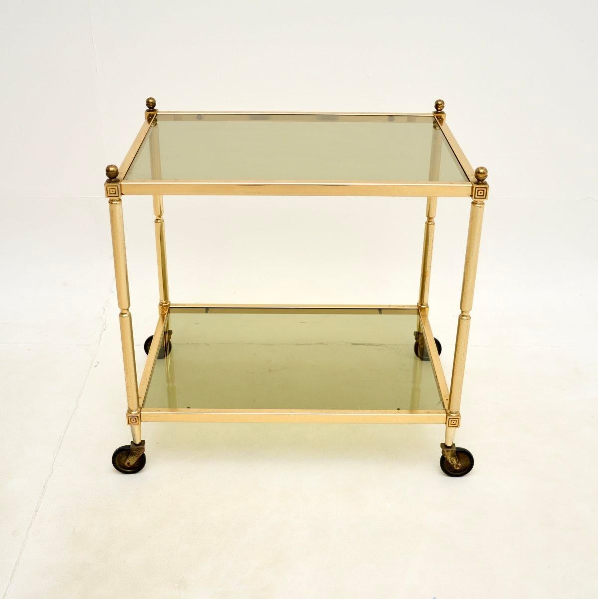 A stylish and very well made vintage French brass drinks trolley, dating from the 1950-60’s.

This is beautifully designed and is of lovely quality. It is quite petite, it has inset glass shelves, acorn finials at the top corners and it rolls