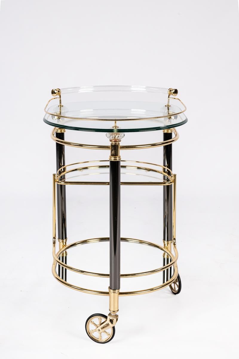 
This bar trolley is designed in the Hollywood Regency style and combines luxury with functionality. The design features three tiers: the bottom tier is a beveled mirror, the middle tier is a glass plate, and the top tier is a beveled glass plate.