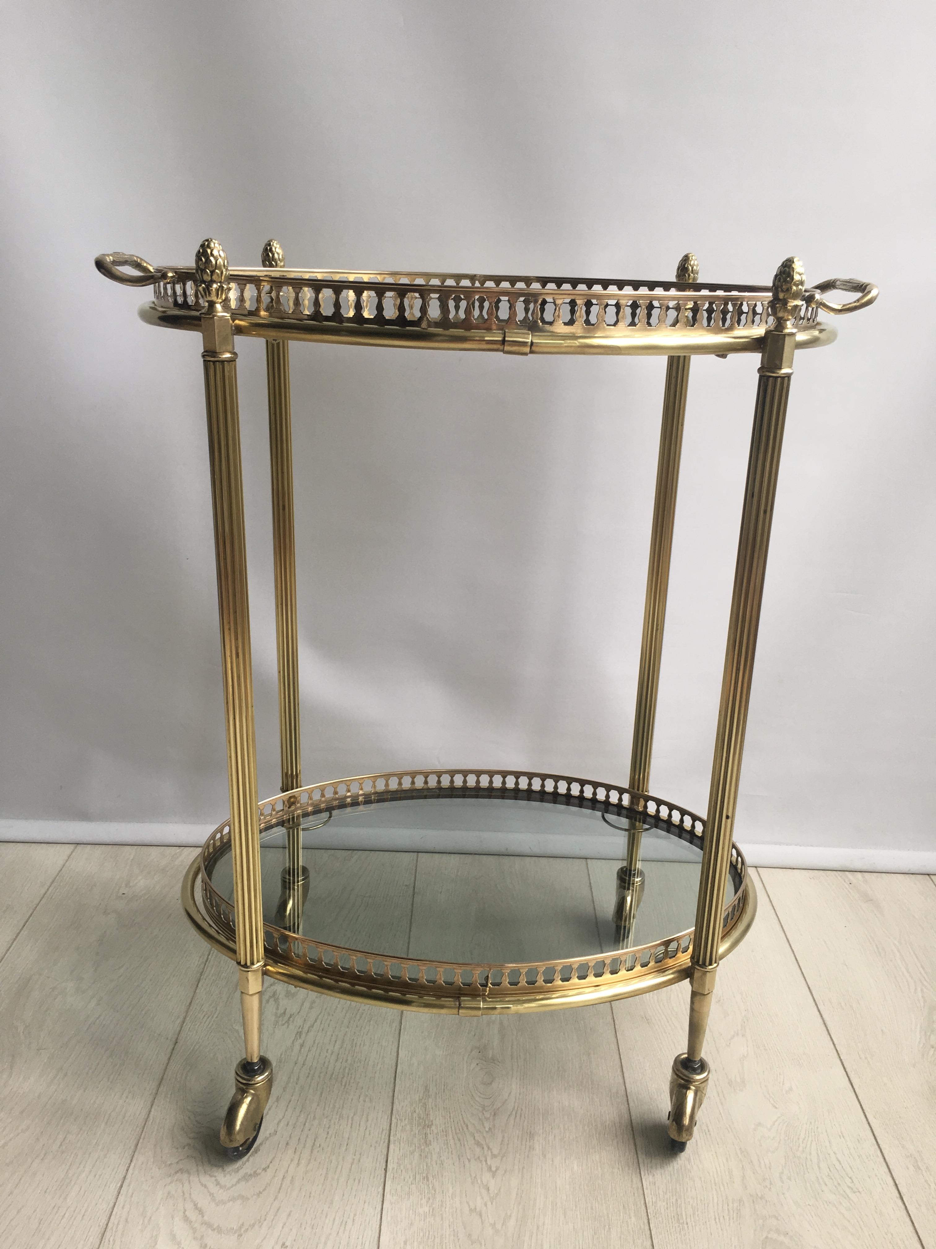 Vintage oval drinks trolley from France, circa 1950.

Polished brass frame with lift off top tray. 

Smoked grey glass trays.

Perfect for smaller spaces.

Overall dimenions 53cm wide, 34cm deep and 66cm tall (62cm to glass).