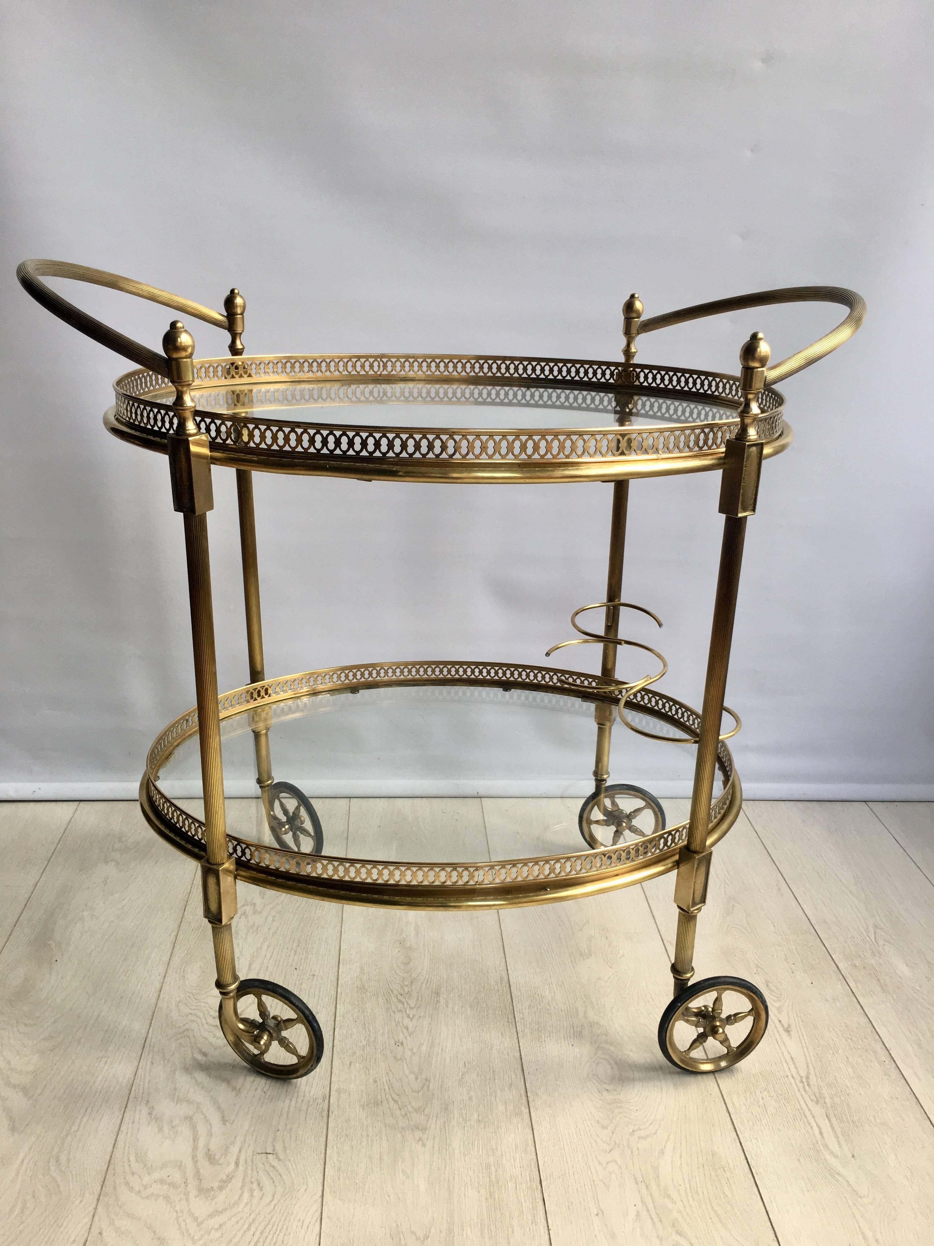 A large oval drink trolley from France, circa 1950

Polished brass frame with decorative handles

The top tray measures 62.5cm wide by 46cm deep and stands 63.5cm to the glass.
Overall dimensions including the handles takes it to 76cm wide,