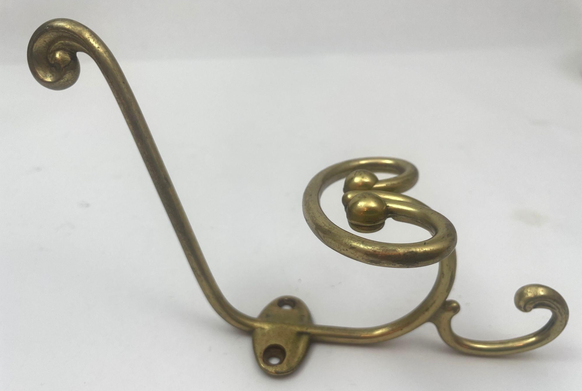 Elevate your space with this exquisite vintage French cast brass triple coat and hat hook from the early 1950s.
This elegant piece features a robust curled bar designed to securely hold your coats and heavier garments, complemented by a smaller hook