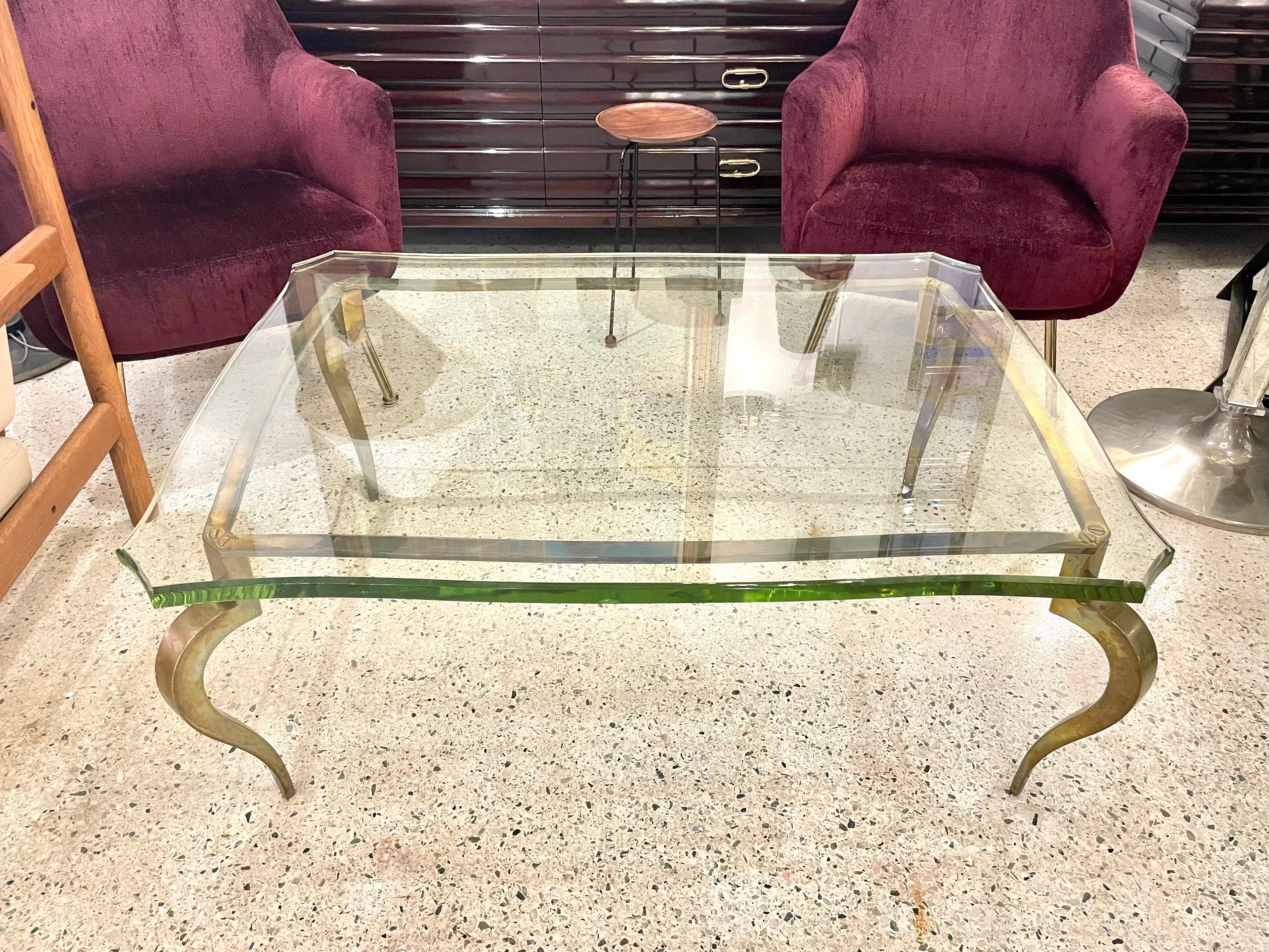 This extremely well designed bronze coffee table with cabriolet legs and French screw accents, the entire table base has an appropriately aged patina. The 1 inch thick beveled green hue scalloped glass is vintage and in wonderful condition. This is