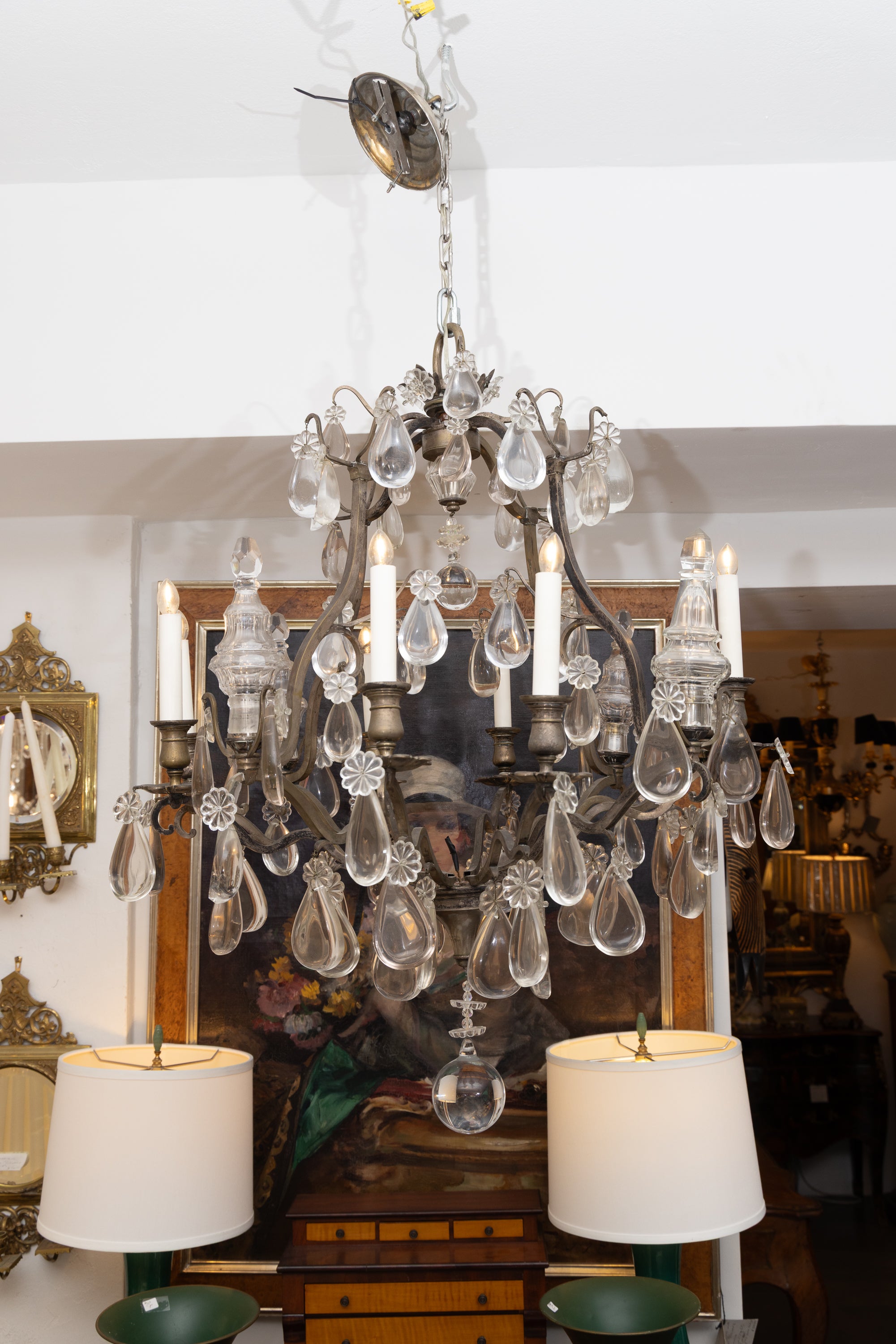 Si tratta di un classico lampadario francese vintage in metallo bronzato a 12 luci con quattro guglie in vetro illuminate.  L'intero lampadario è abbondantemente appeso con  ciondoli a goccia in vetro di rilievo.