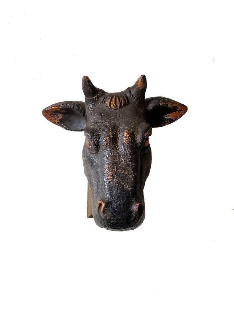 A vintage French steer's head, used as the sign of a butcher’s shop, usually hung over the door. The beautiful eary to mid 20th century cow head bust was hand-crafted in France, likely after an original zinc model. 

The hand carved and painted