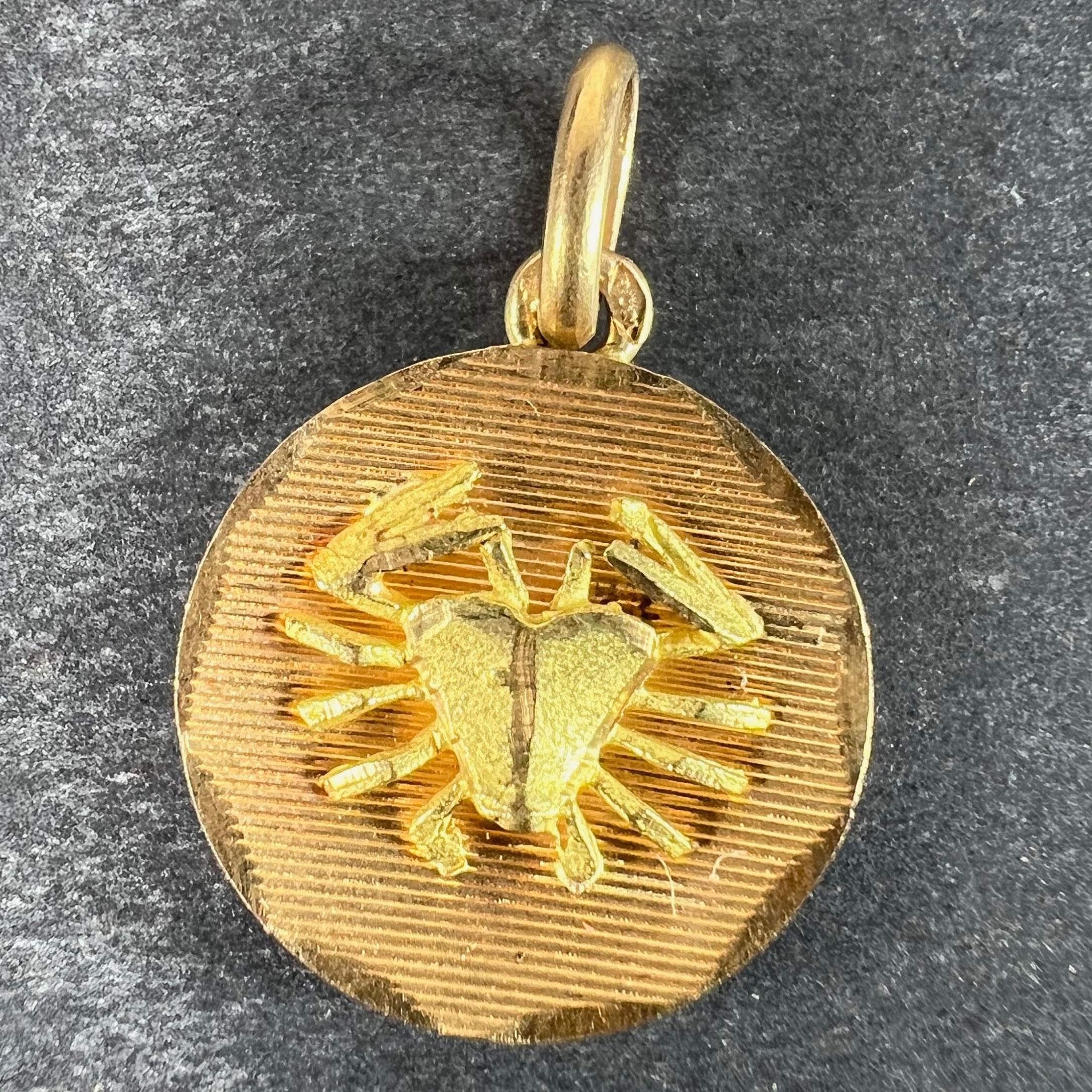 Ciondolo charme francese in oro giallo 18 carati (18K) disegnato come una medaglia rotonda concava incisa con linee orizzontali con un granchio opaco in rilievo attaccato al centro, che rappresenta il segno zodiacale del Cancro all'interno di una
