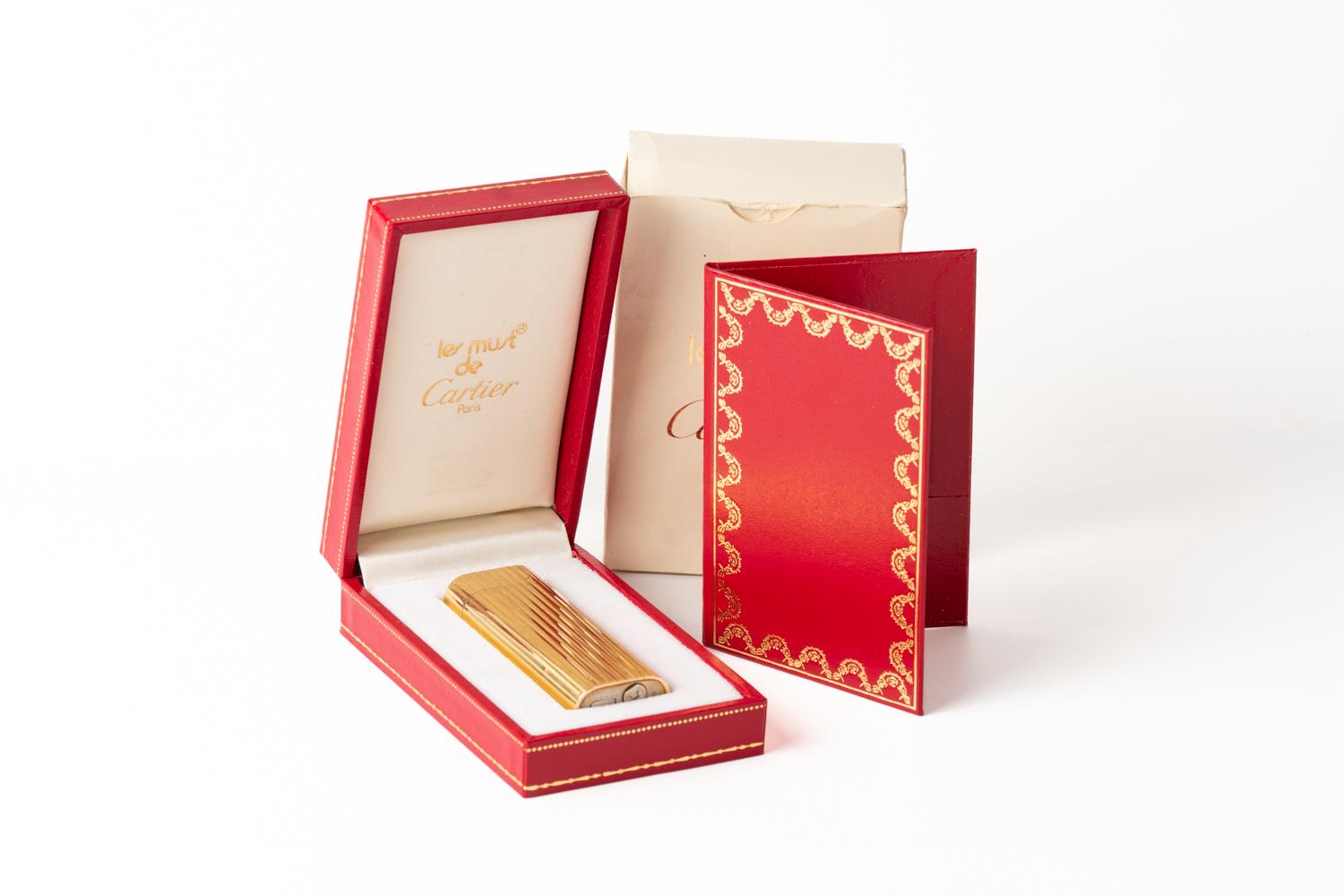 Classic and iconic vintage Must De Cartier Stripe Gold Plated Lighter with original red Cartier box and Cartier extractor. The bottom of the lighter is stamped 'Cartier', 'Paris', and 'SWISS MADE' with serial number: 46637D. The lighter is not in a
