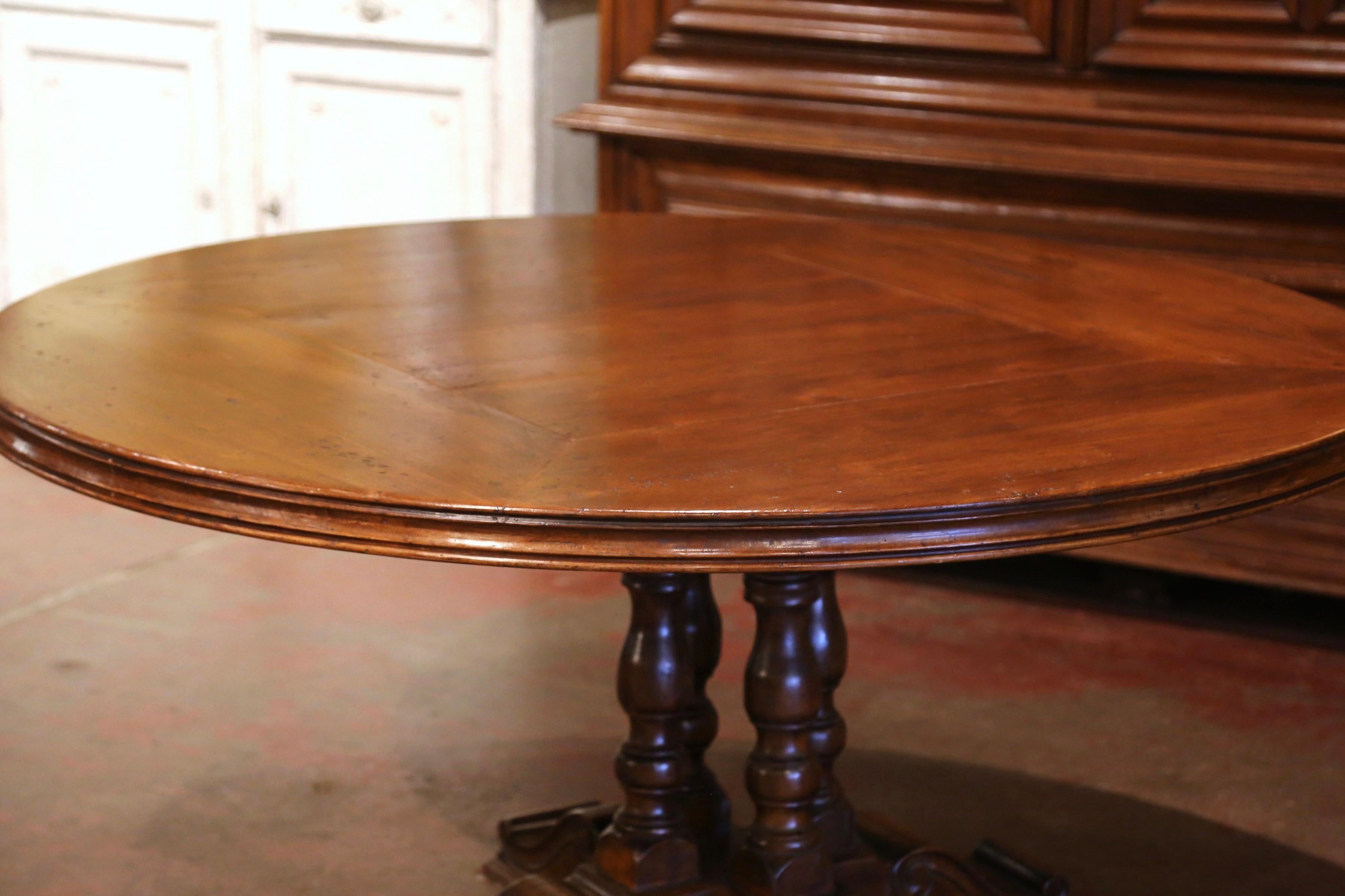 Crafted in the Pyrenees mountains of France circa 1990, and built with old walnut timber, the table stands on a four carved and turned columns pedestal base, supported by flat and carved feet for ultimate stability. The sturdy table dressed with a
