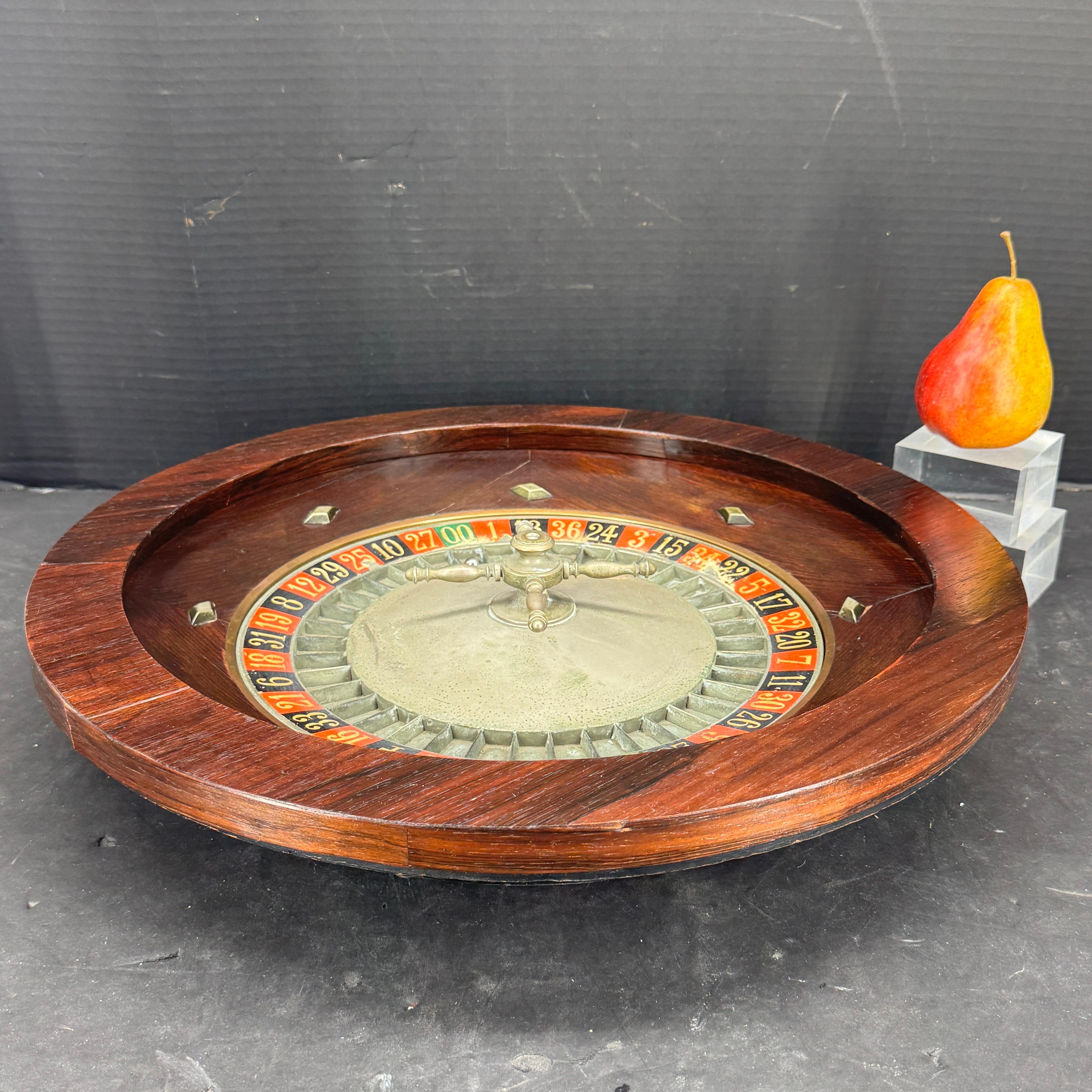 An 1950's French roulette wheel stamped Roulette Francaise, Marque Depose. This casino roulette wheel features the original metal numbers as well as the roulette ball, all surrounded by the original walnut wood casing. We see this piece for a