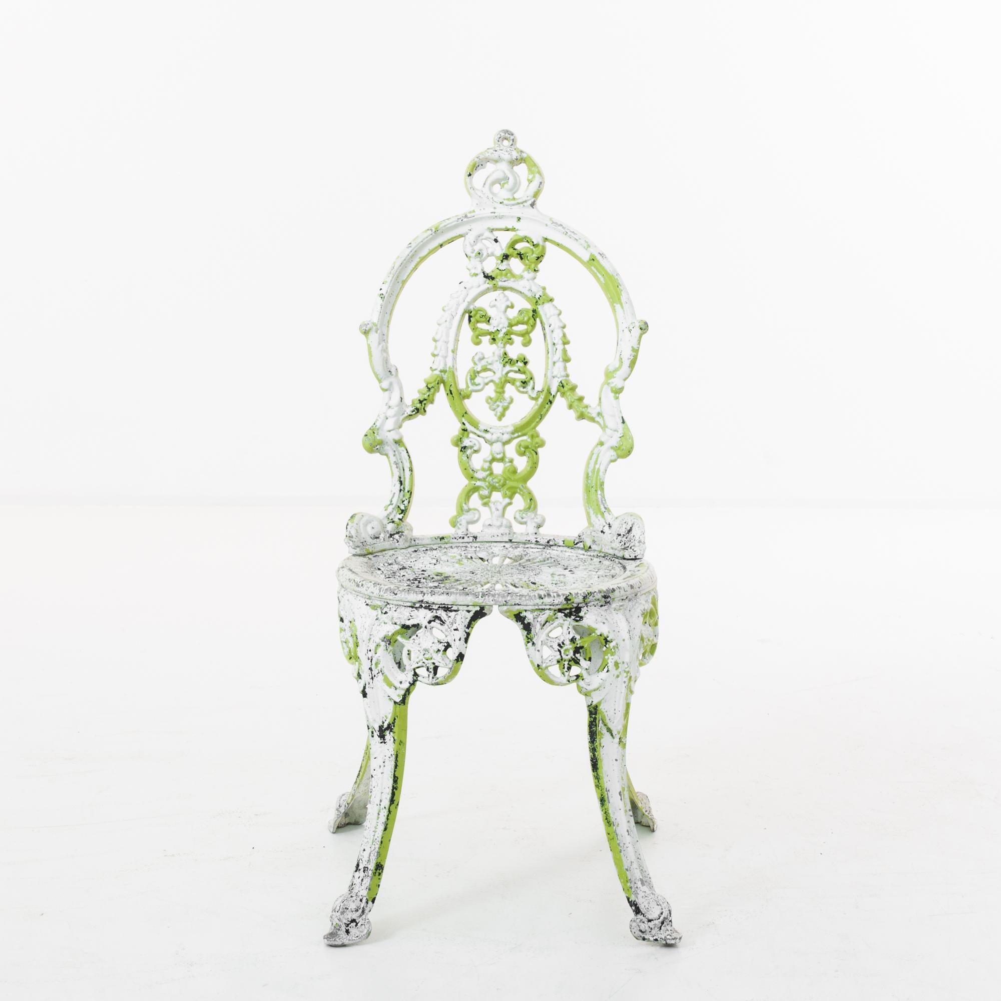 A cast iron chair from France, produced circa 1960. A richly decorated garden chair with white and green patination. This cast metal seat stands out for its unique vivid green patination coming out in artful patches, as well as for the ornate trim