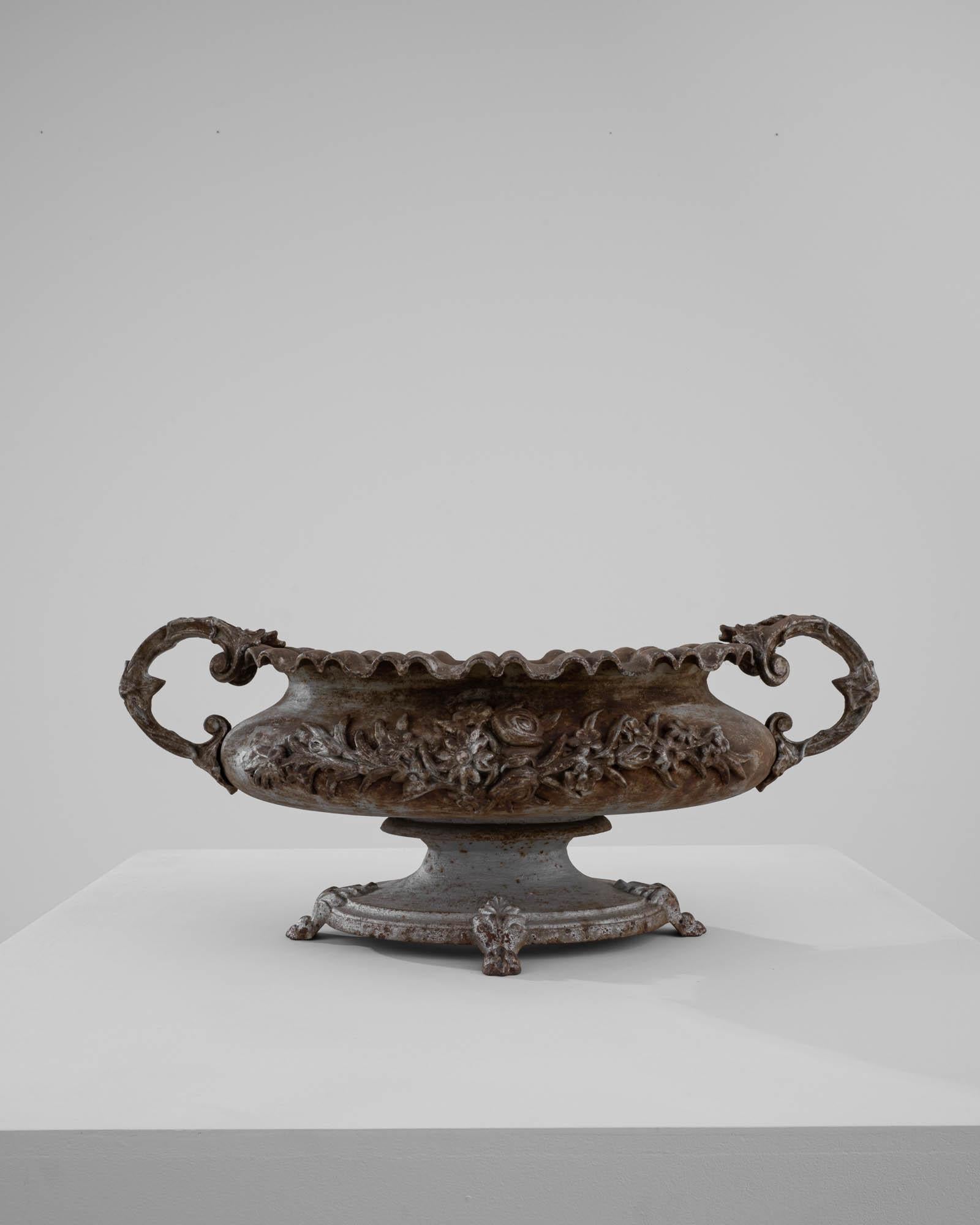 A cast iron planter from France, made in the 19th Century. The campana shape resembled an upturned bell with a fluted cupola and broad lip, reminiscent of an opening blossom. Weathered over the years, the cast iron has acquired a striking layered