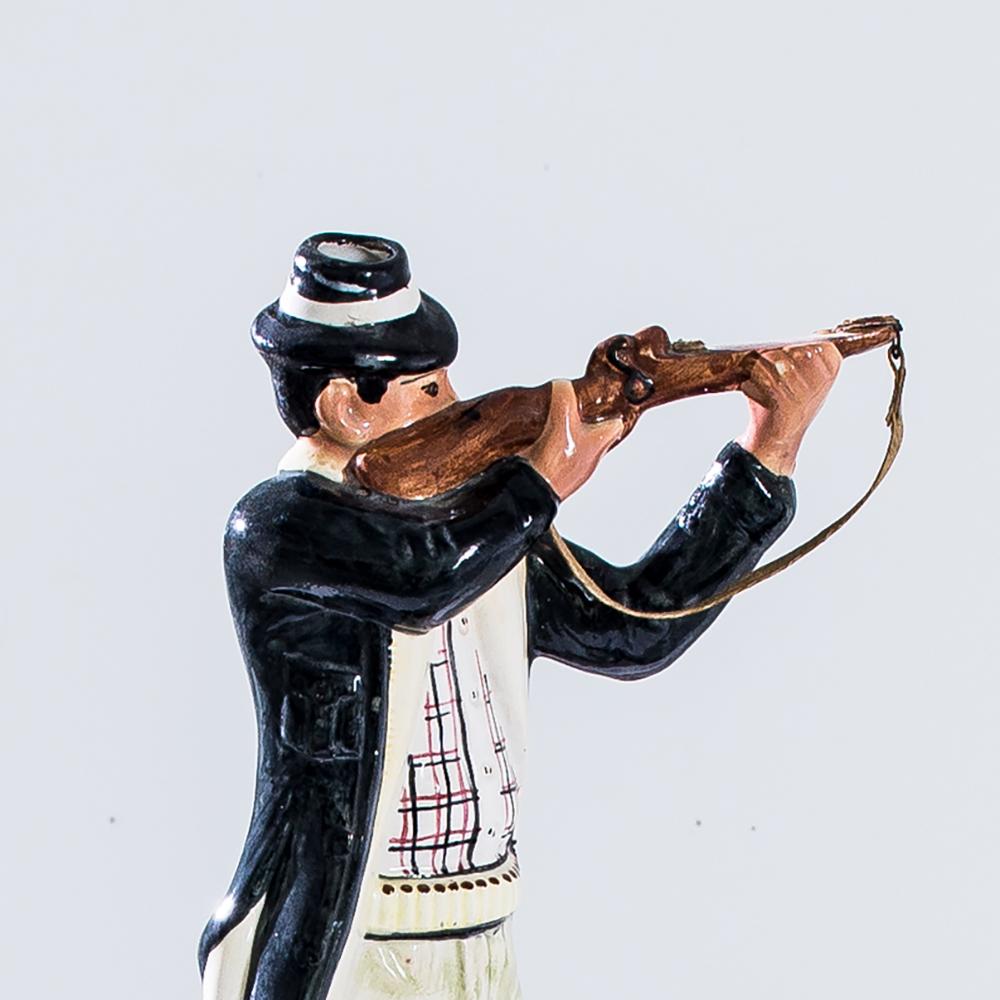 A glazed ceramic bottle, depicting a hunter standing on top of a pointer dog. Made in France between 1950 and 1960, a wealth of charming detail lends verisimilitude to the absurd scene: the chequered hunting vest, the leather rifle strap, the intent
