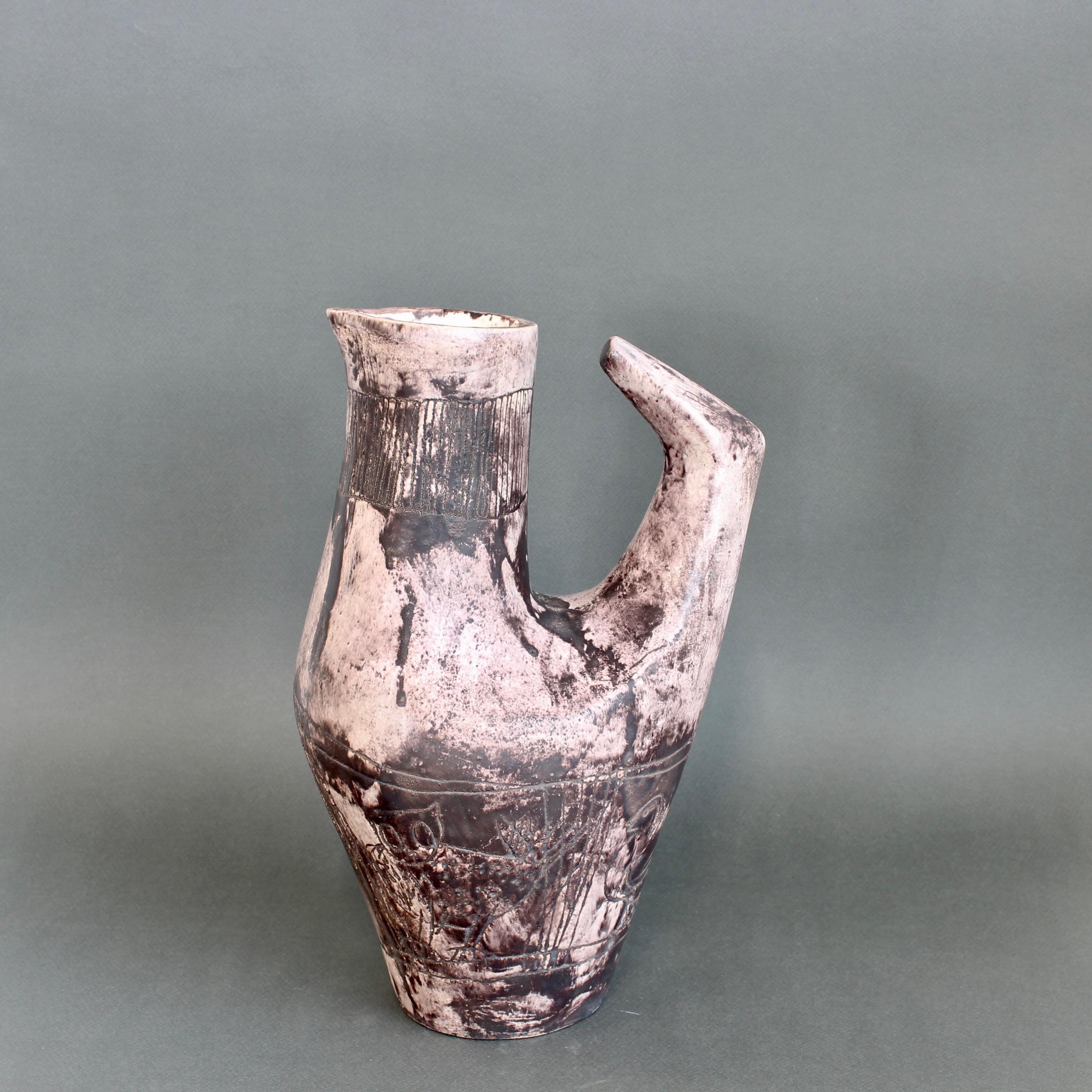 Brocca decorativa in ceramica francese d'epoca (circa anni '50) di Jacques Blin. Il vaso è di una sottile tonalità magenta, ricoperto dallo smalto nebbioso tipico di Blin. È decorato con diversi uccelli incisi di vario tipo intorno al corpo