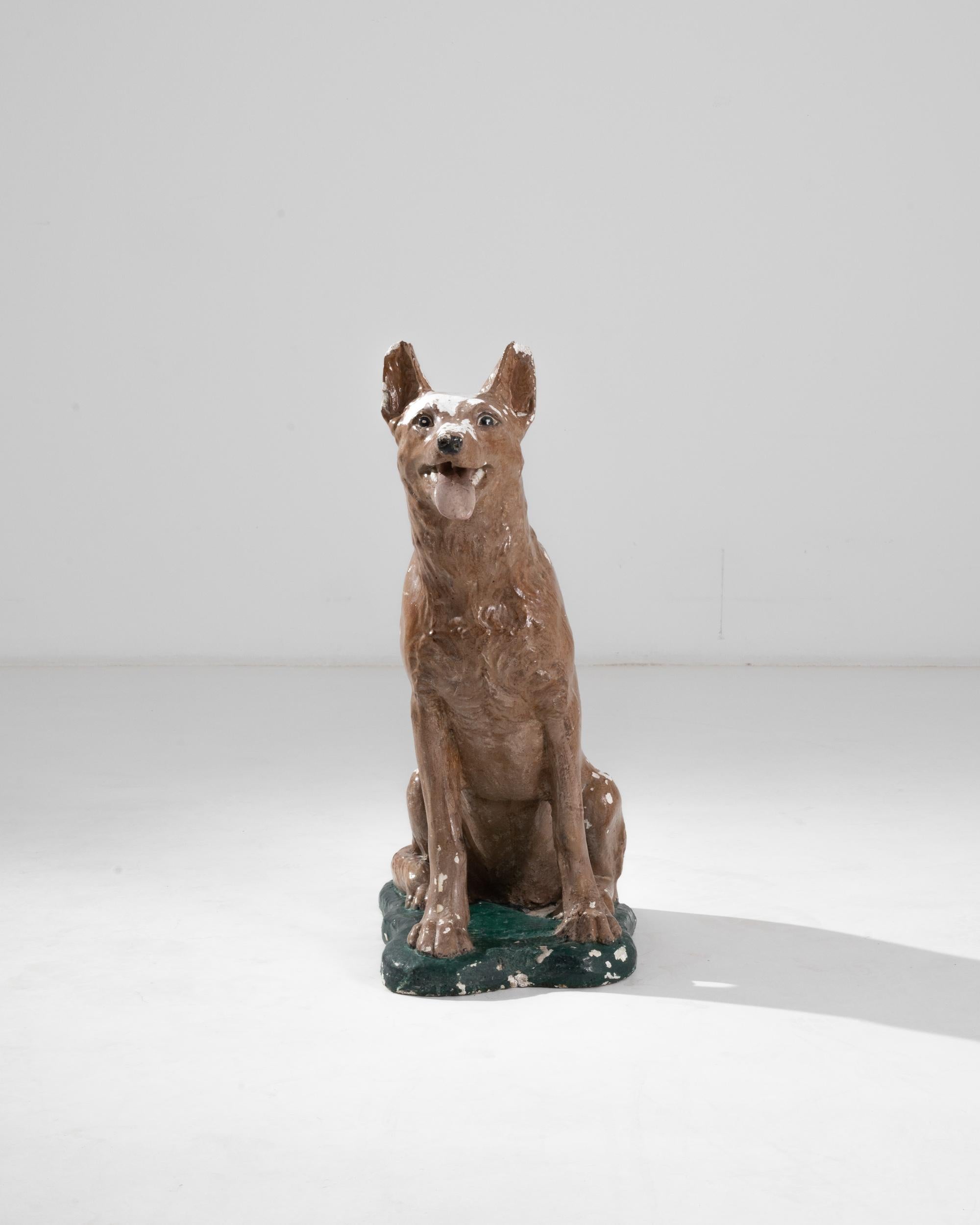 A vintage ceramic sculpture depicting a German Shepherd, seated attentively on its haunches. Made in France in the 20th century, the piece is roughly life-sized and painted with loving attention to detail. Though the colorful surface has weathered