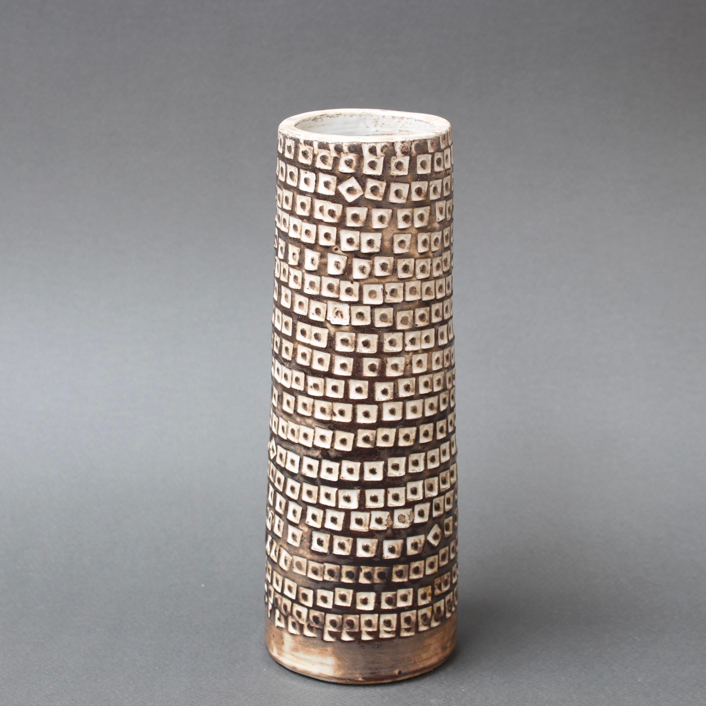 Dekorative zylindrische Blumenvase aus Keramik (um 1960), von Jacques Pouchain. Die Dekoration dieser Vase aus der Mitte des Jahrhunderts hat etwas Stammesmäßiges an sich. Die geometrischen Formen in Weiß, jede mit einem braunen Fleck, bilden ein