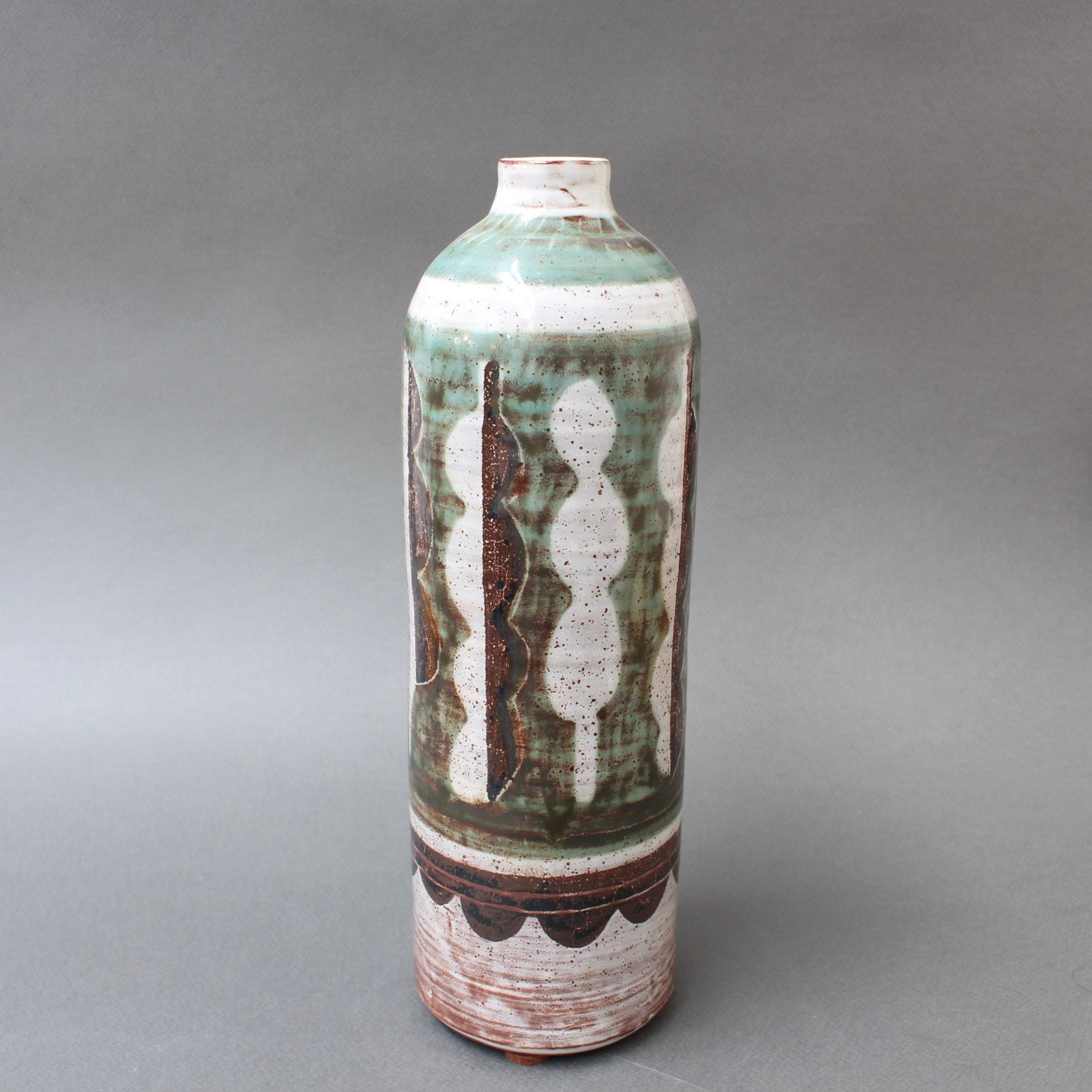 Midcentury ceramic flower vase (circa 1960s) by Michel Barbier. A tall single-flower vase with abstract motif combining a jade green and brown over an off-white elegant glaze with small specks. The understated colors of the vase means the piece will
