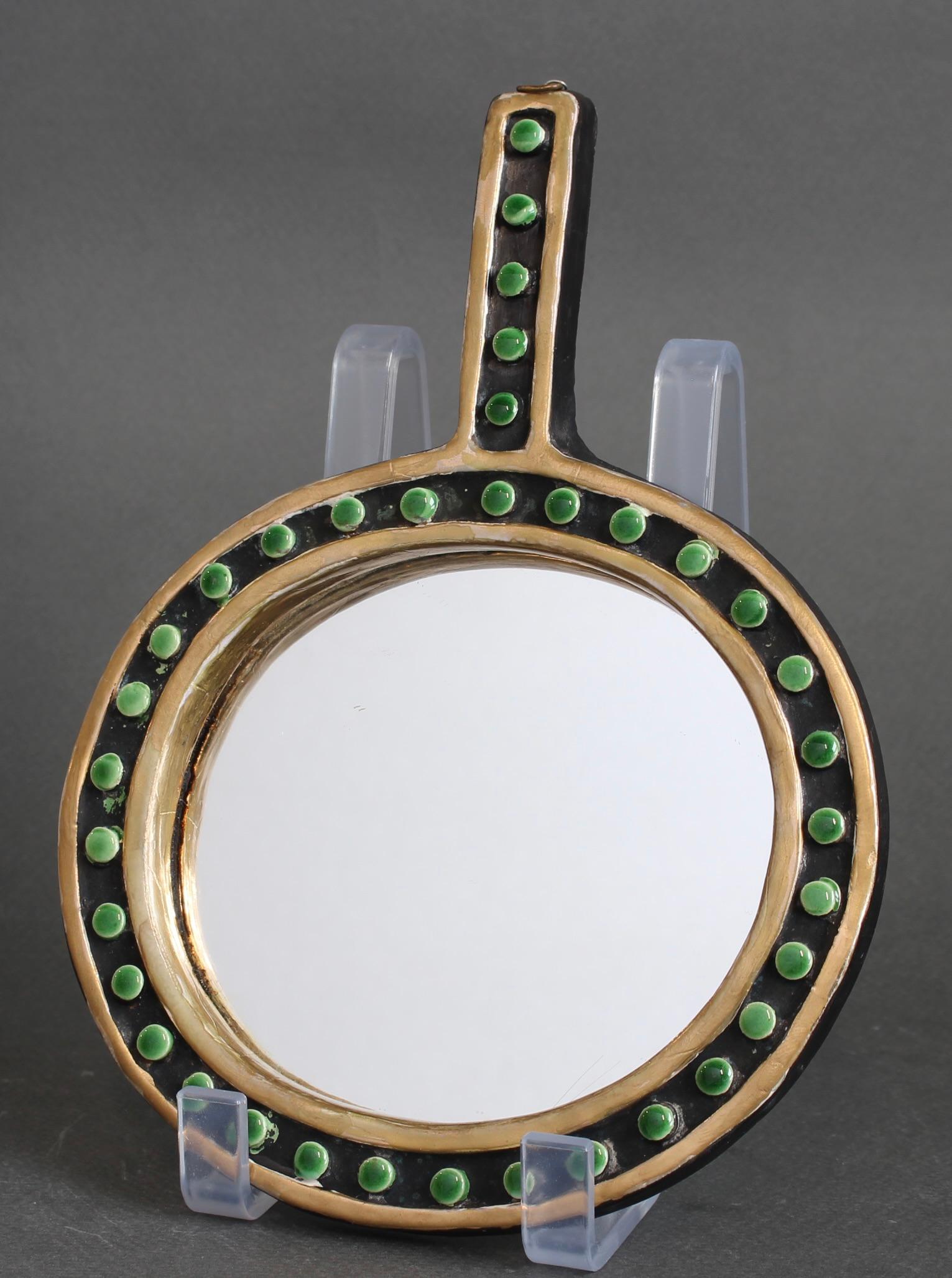 Miroir à main circulaire en céramique de Mithé Espelt (vers les années 1970). Cette charmante pièce d'art décoratif présente des bordures dorées et de délicieuses perles d'émail dans des tons verts. Cette pièce accompagnerait à merveille un meuble