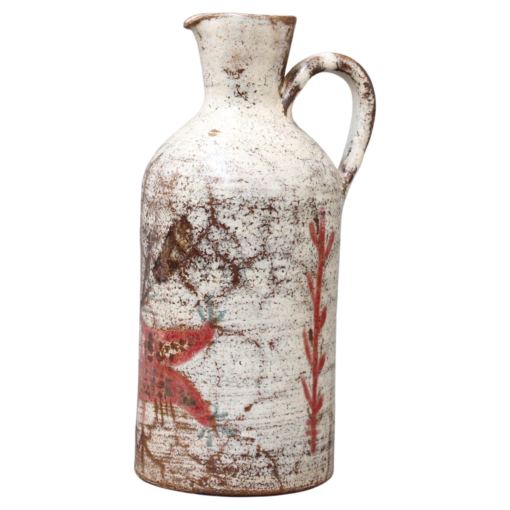 Vintage French ceramic jug by Le Mûrier (circa 1960s). A delightful ceramic piece with curved handle and a spout with lip. A creamy white lustrous glaze with brown patches form the base of the piece complemented by a red stylised bird and