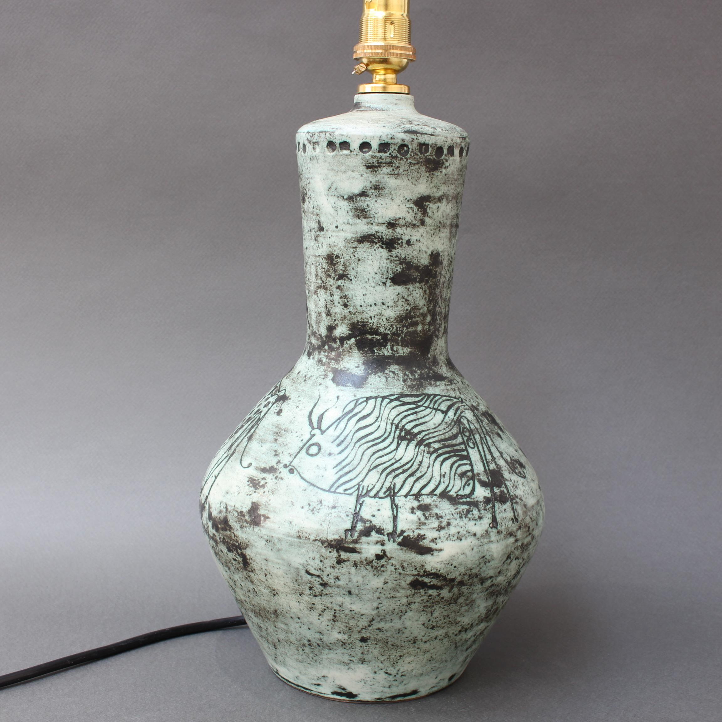 Ceramic lamp (circa 1950s) by Jacques Blin (1920-1995). This lamp has Blin's signature cloudy glaze featuring etchings of fanciful images of what appear to be animals from ancient cave drawings. The lamp is in good vintage condition and is highly