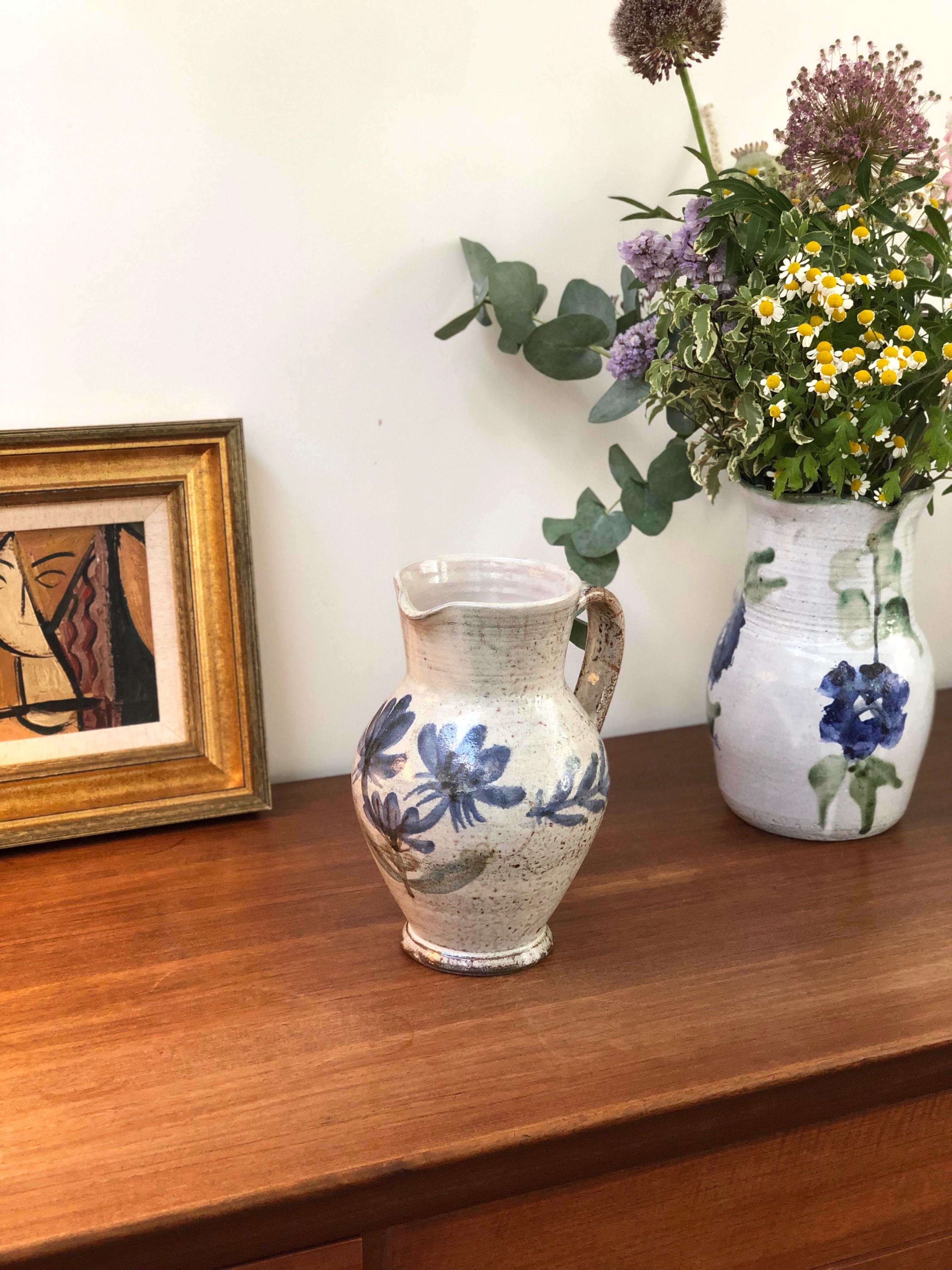 Vintage ceramic pitcher / vase by Gustave Reynaud, Le Mûrier, circa 1950s. This utilitarian pitcher is also a delightful work of art doubling as a beautiful vase. On the rustic exterior you will find lovely flowers with blue petals under the spout
