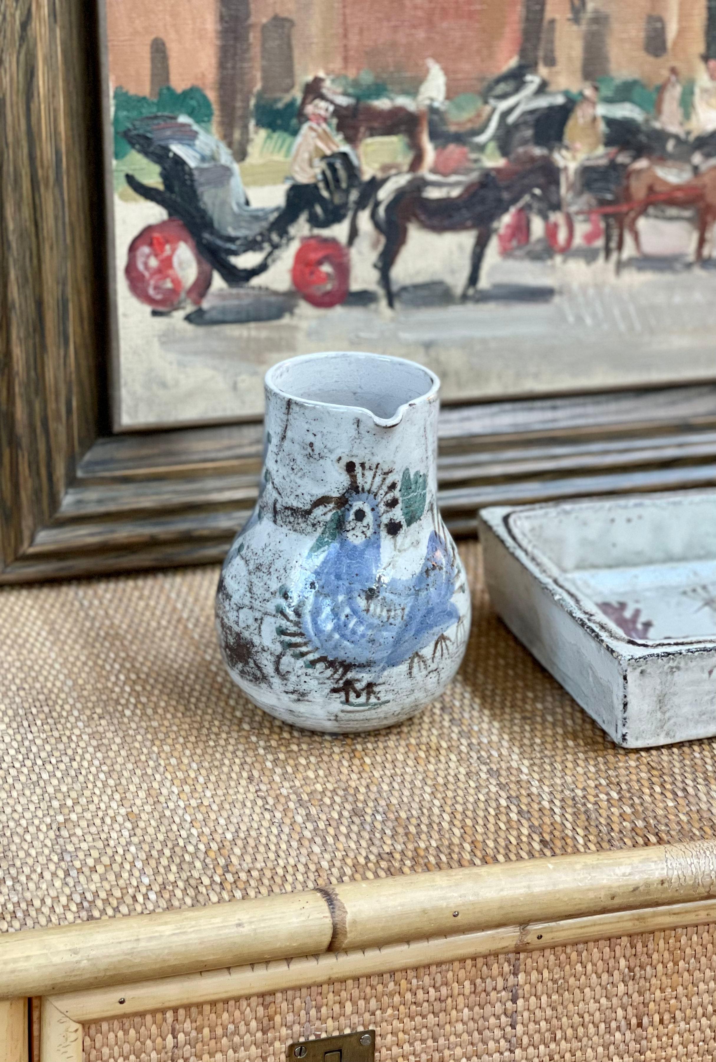 Vintage French ceramic pitcher by Gustave Reynaud - Le Mûrier (circa 1960s). A delightful ceramic piece with graceful handle in a hazy, creamy white glaze as base. The French rooster is decorated on the body with shrubbery and plants throughout.