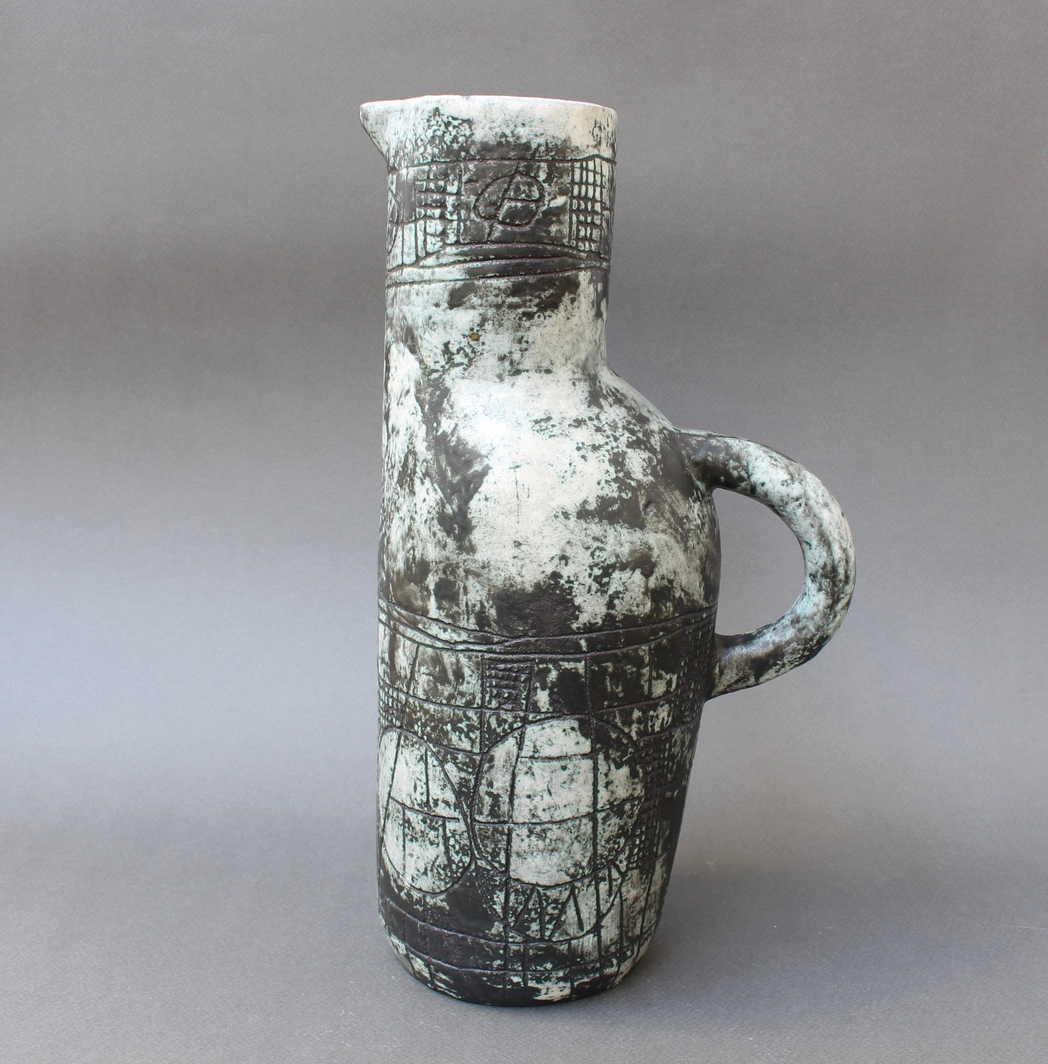 Vintage French ceramic pitcher by Jacques Blin (circa 1960s). Unique in its style and decoration, its form is zoomorphic with incised decor of geometric shapes. Of course Jacques Blin's trademark misty glaze and light green patina make this piece a