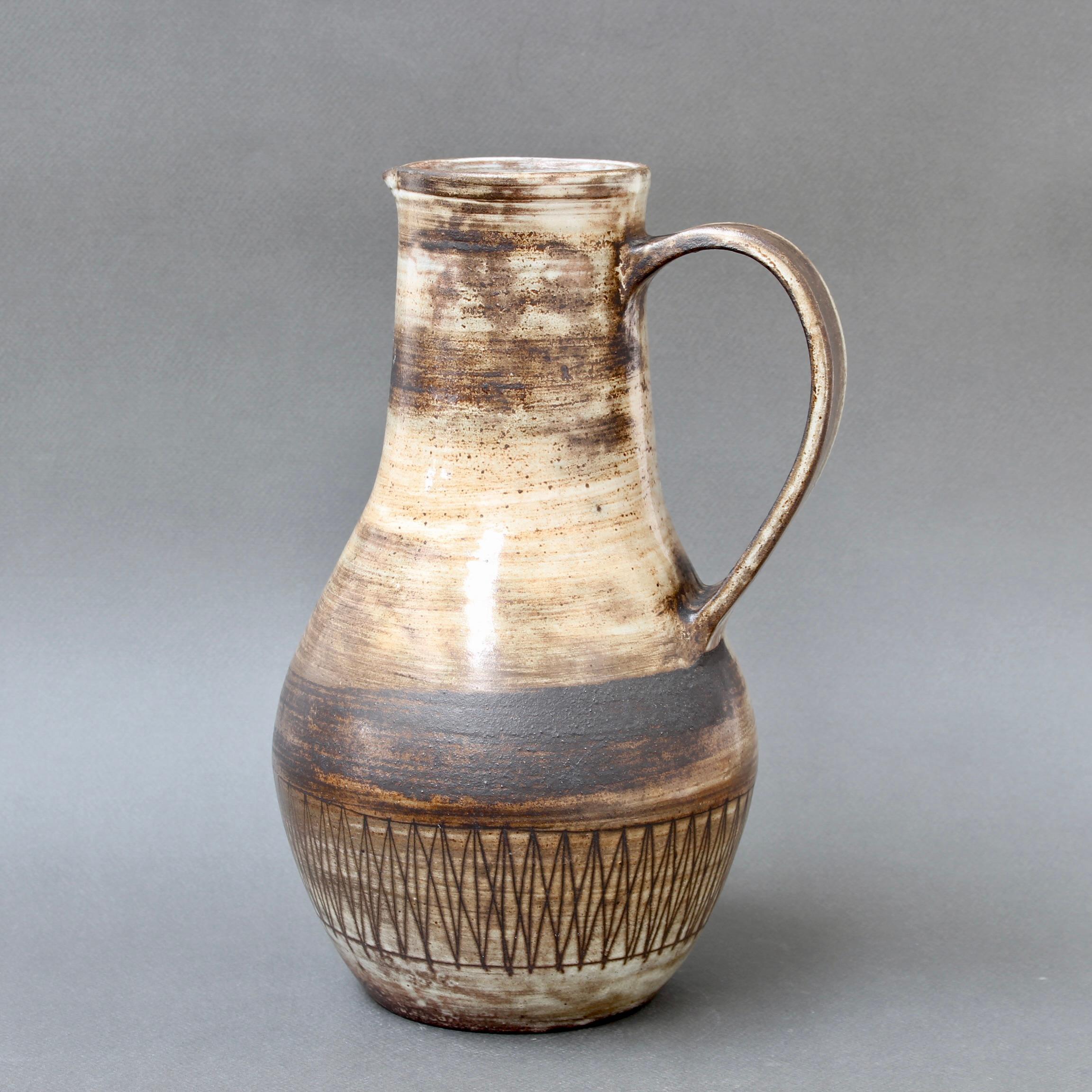 Mid-century ceramic pitcher by Jacques Pouchain / Atelier Dieulefit (circa 1960s). Classically-shaped piece in Pouchain's signature cloudy glaze style with earth tone hues. It is elegant with a contemporary motif surround of lines and geometric