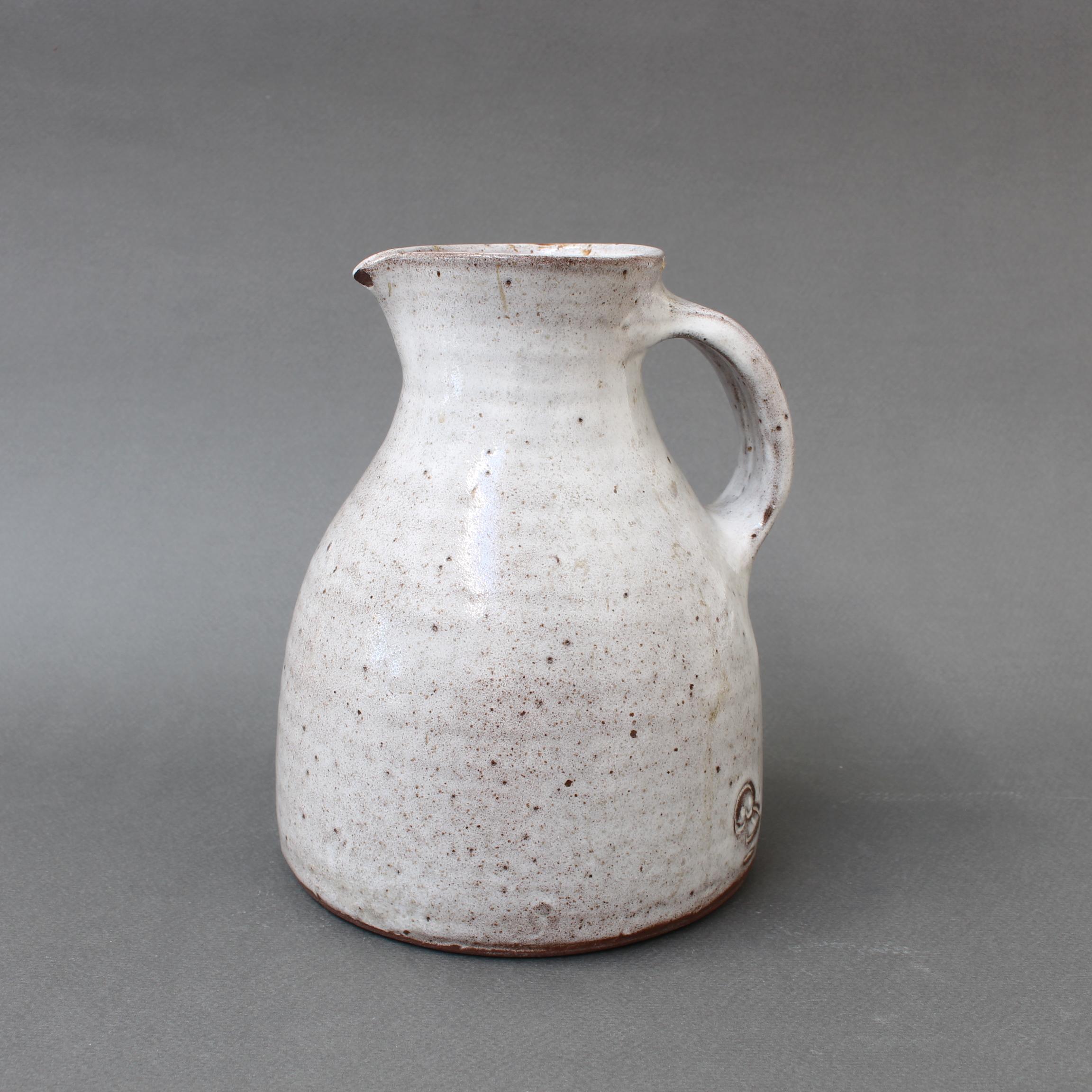 Mid-Century French ceramic pitcher by Jeanne & Norbert Pierlot (circa 1960s). With an off-white base and brown sandstone accents, Pierlot's rustic pitcher with handle and spout is a delight. The glazed parts that are predominantly off-white are
