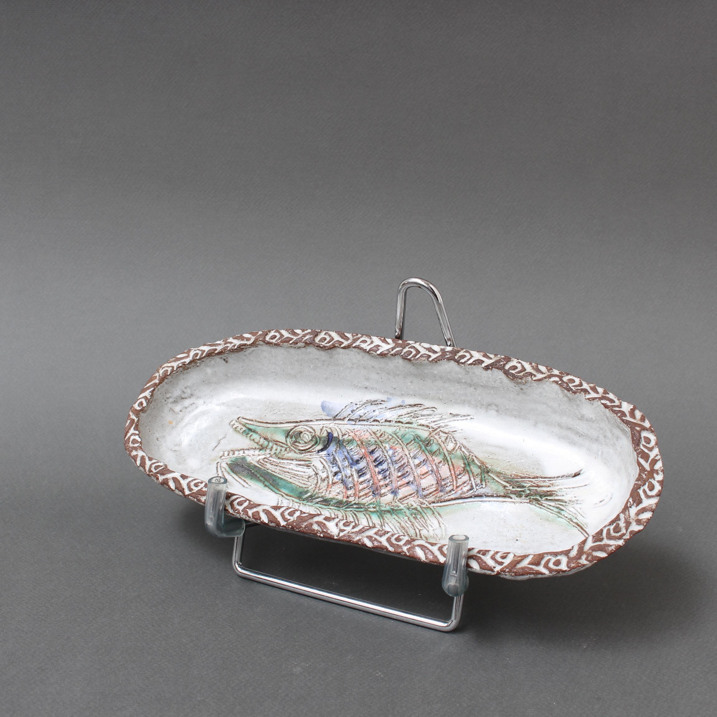 Plat décoratif en céramique française à motif de poisson (circa 1970) par Albert Thiry. Un plat en céramique de forme ovale est recouvert d'une glaçure blanche comme de la craie. Dans le creux du plat, un poisson est incisé dans la glaçure et peint