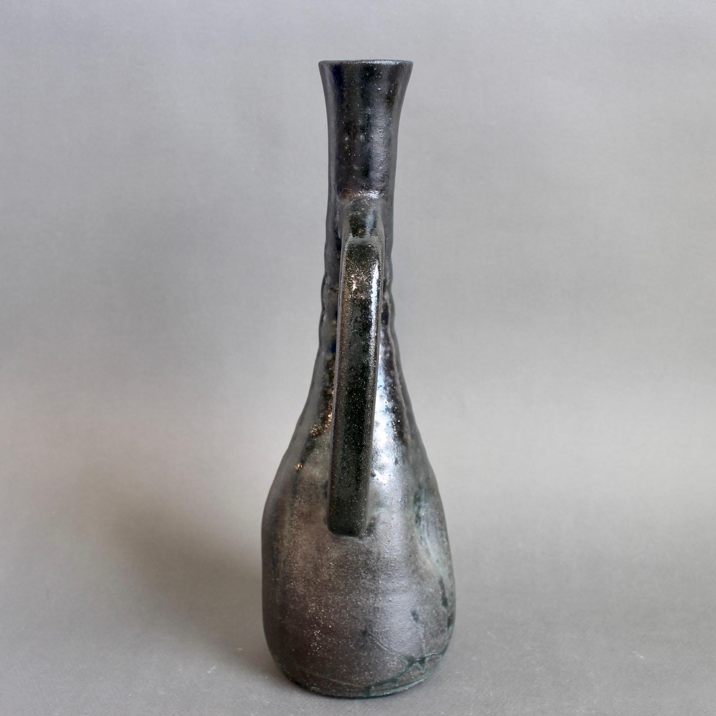 French ceramic vase by Accolay (Circa 1960s). An elegantly elongated flower vase with both matt and lustrous black sections provides surprise and delight. The shape takes inspiration from classicism but with a modern interpretation incorporating