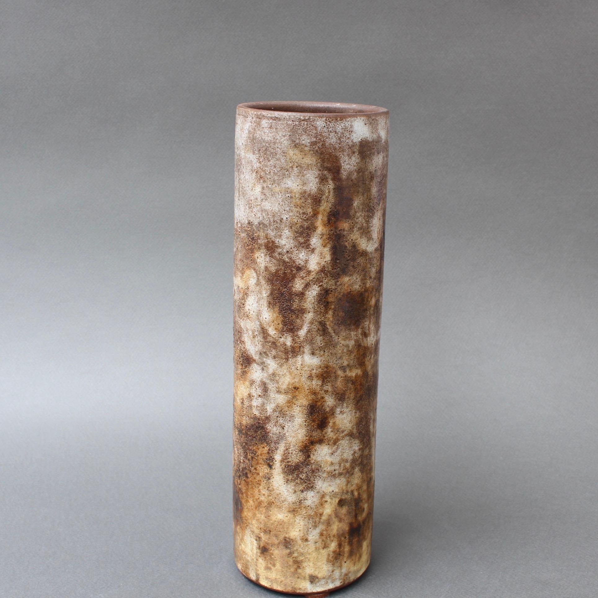 Vase en céramique française d'Alexandre Kostanda, (vers les années 1960). Ce magnifique récipient cylindrique présente un aspect brumeux avec des tons naturels de terre dans les tons bruns, beiges et de délicates touches de jaune. En plus d'être