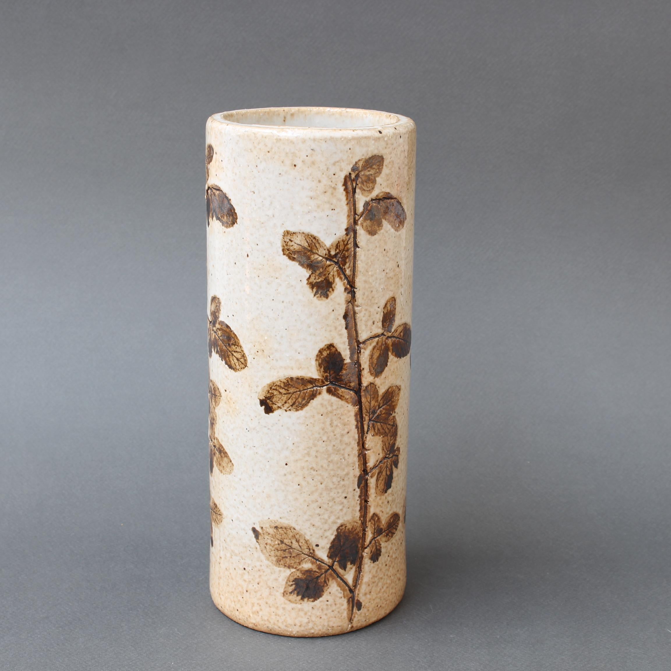 Vase vintage en céramique de Raymonde Leduc (circa 1970). Vase cylindrique en grès avec des motifs végétaux incrustés autour de la pièce. Très charmant dans un style provençal. En bon état général. Dans le style de Roger Capron. Veuillez apprécier
