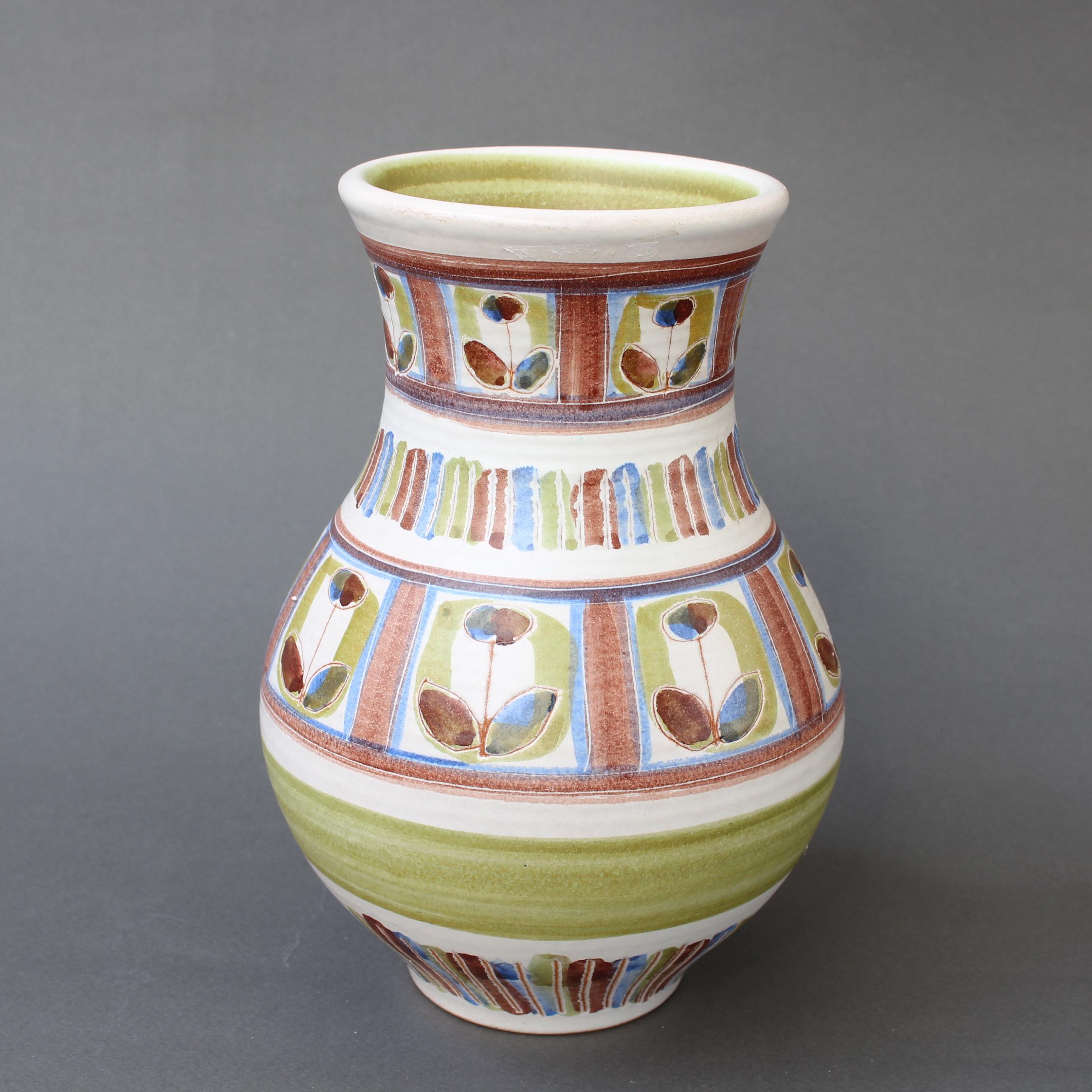 French ceramic vase by Dominique Guillot (circa 1960s). Delightfully decorated with a colourful flower motif, the vase is utilitarian and beautiful all at once. The sensuous, spherical body narrows at the neck and opens wide again at the mouth