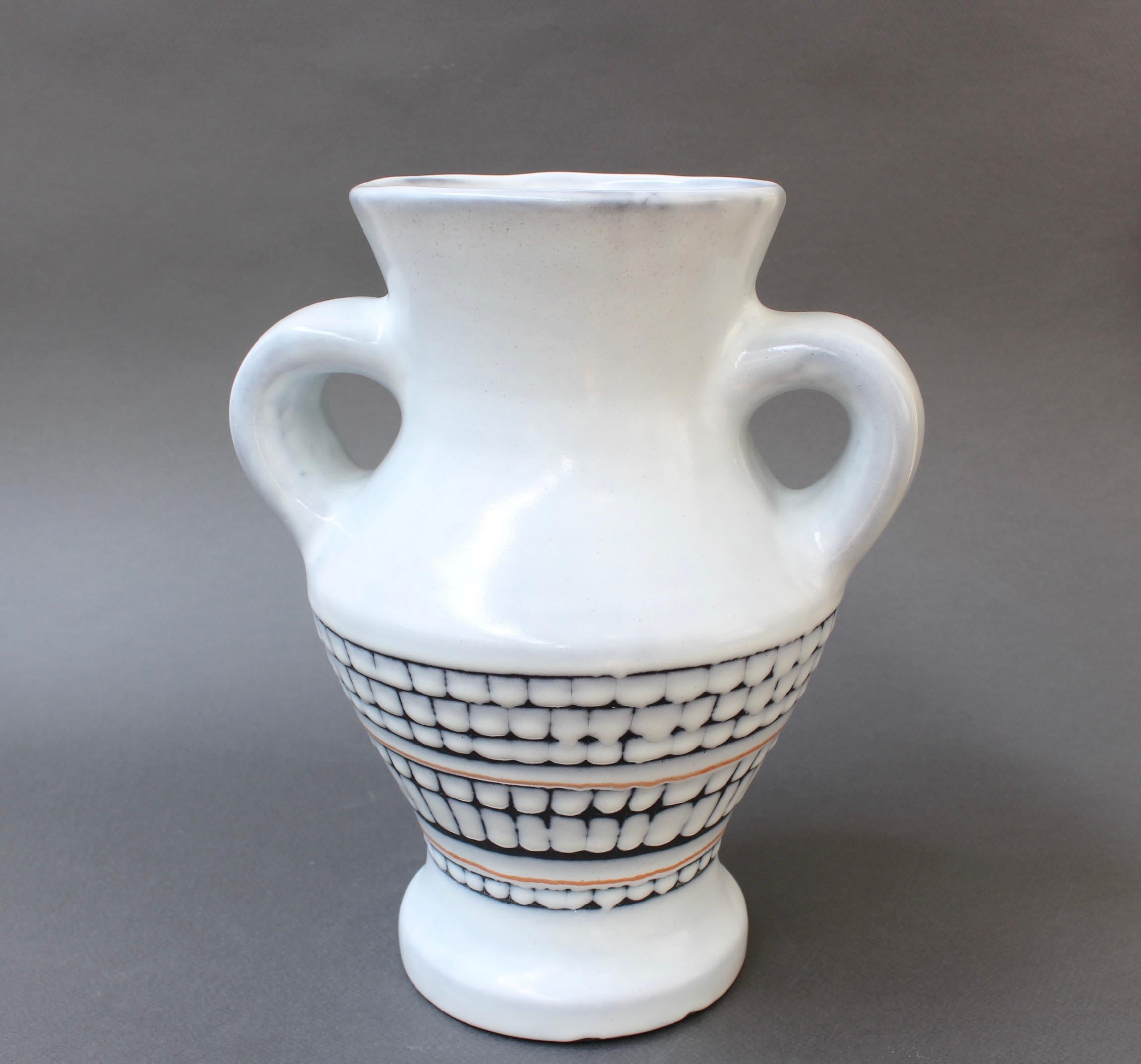 Vaso in ceramica vintage con manici in stile classico del maestro ceramista Roger Capron (circa anni '50). In ottime condizioni generali, lo sfondo bianco gesso è decorato con un motivo a piastrelle dalla metà in giù. Un pezzo di queste dimensioni e